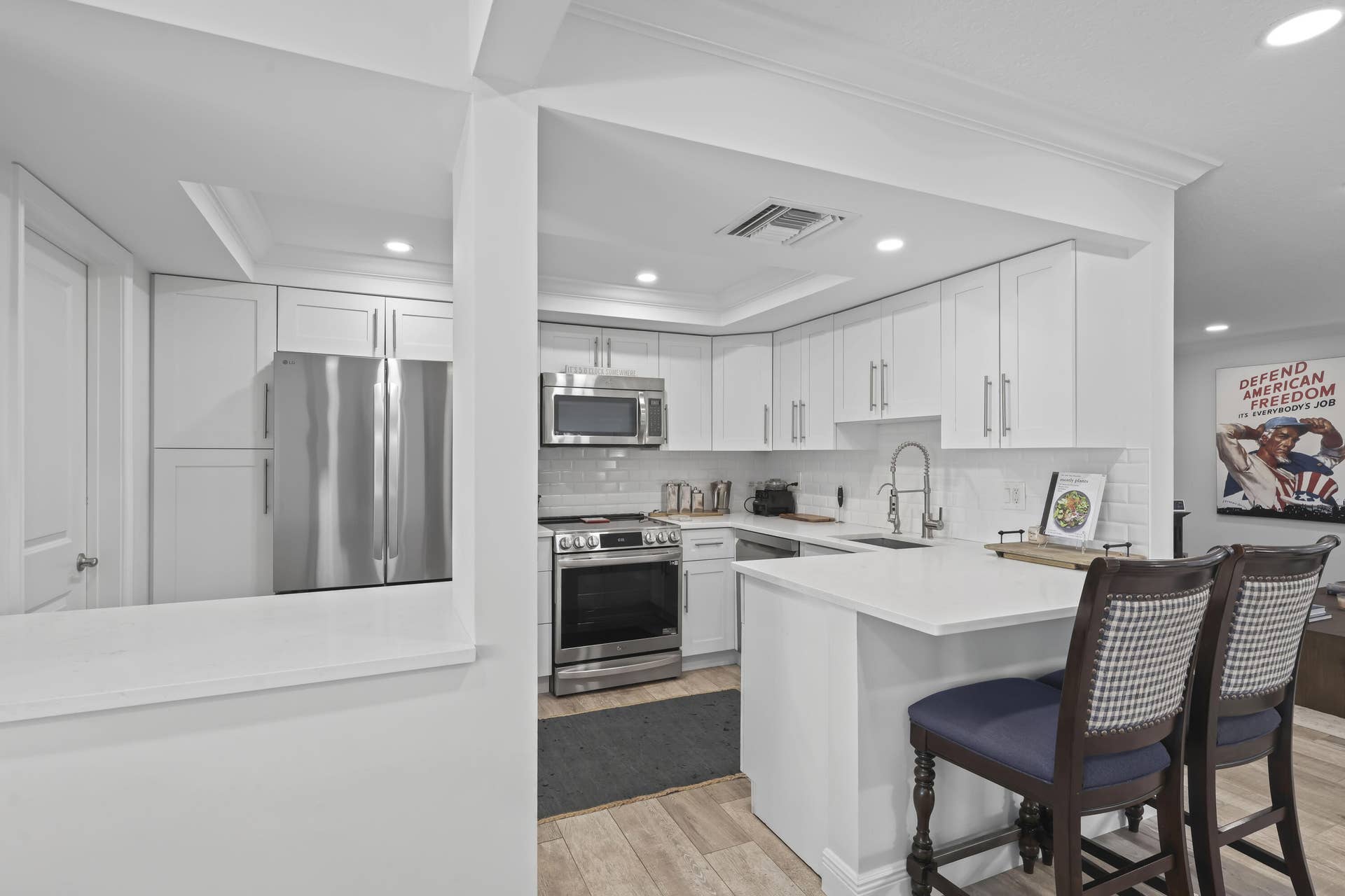 137 Clubhouse Boulevard, Atlantis, FL 33462 Kitchen featuring white cabinetry, quartz countertops, stainless steel appliances, a white subway tile backsplash, and wood-finish flooring