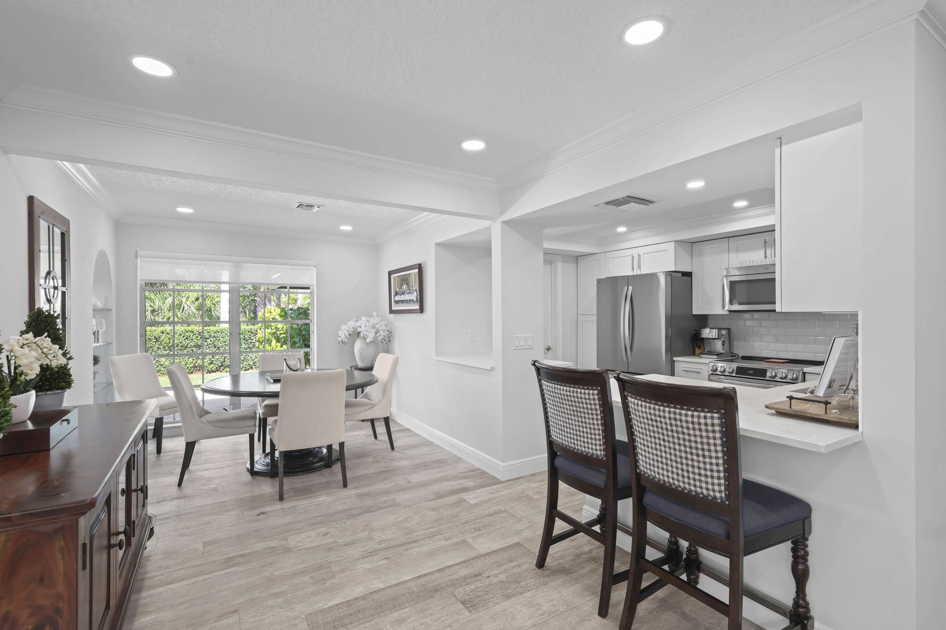 137 Clubhouse Boulevard, Atlantis, FL 33462 Kitchen featuring wood-finish flooring, recessed lighting, stainless steel appliances, stone-surface countertops, and breakfast bar seating