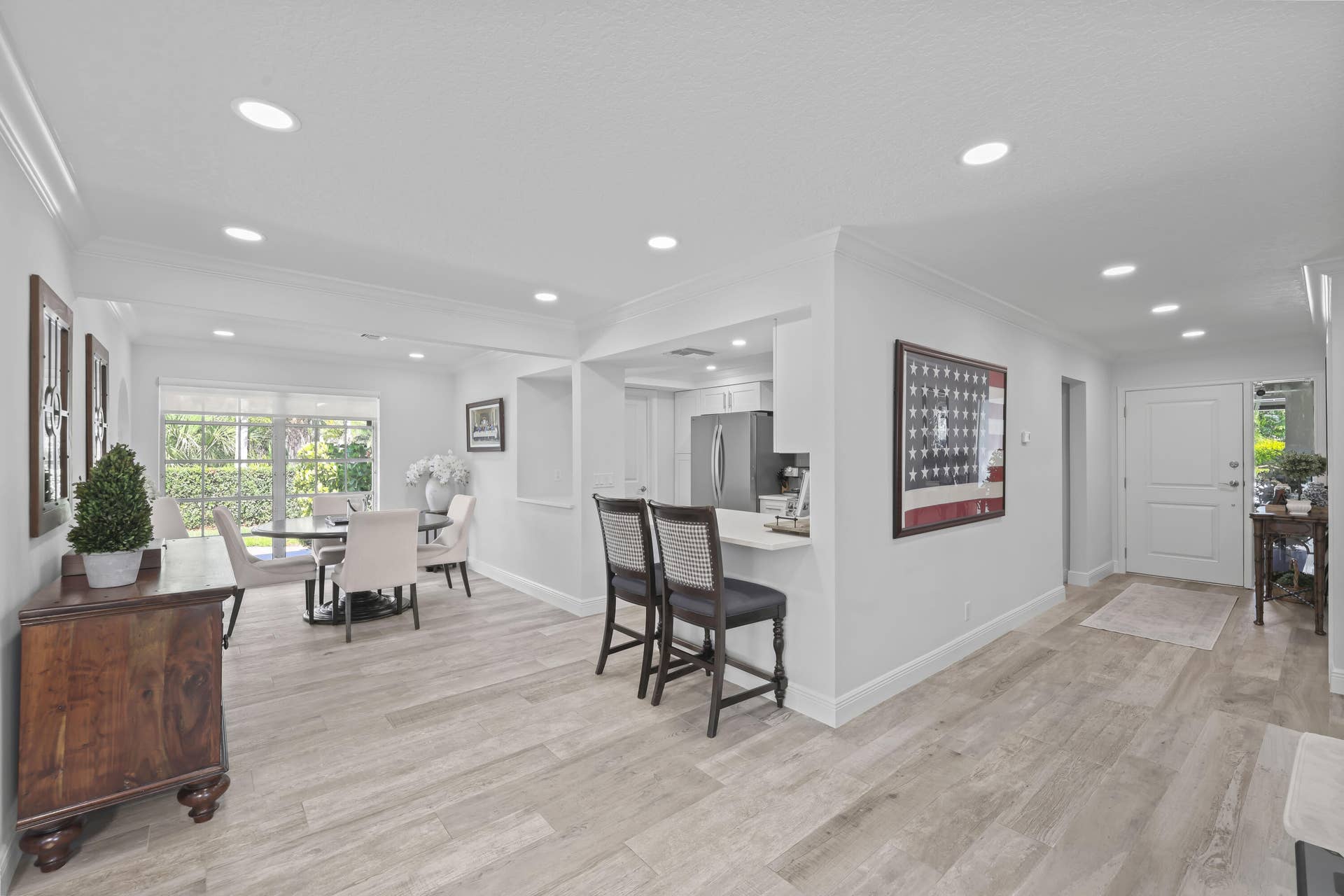 137 Clubhouse Boulevard, Atlantis, FL 33462 Open interior space featuring wood-finish flooring, recessed lighting, and a kitchen breakfast bar with solid-surface countertop
