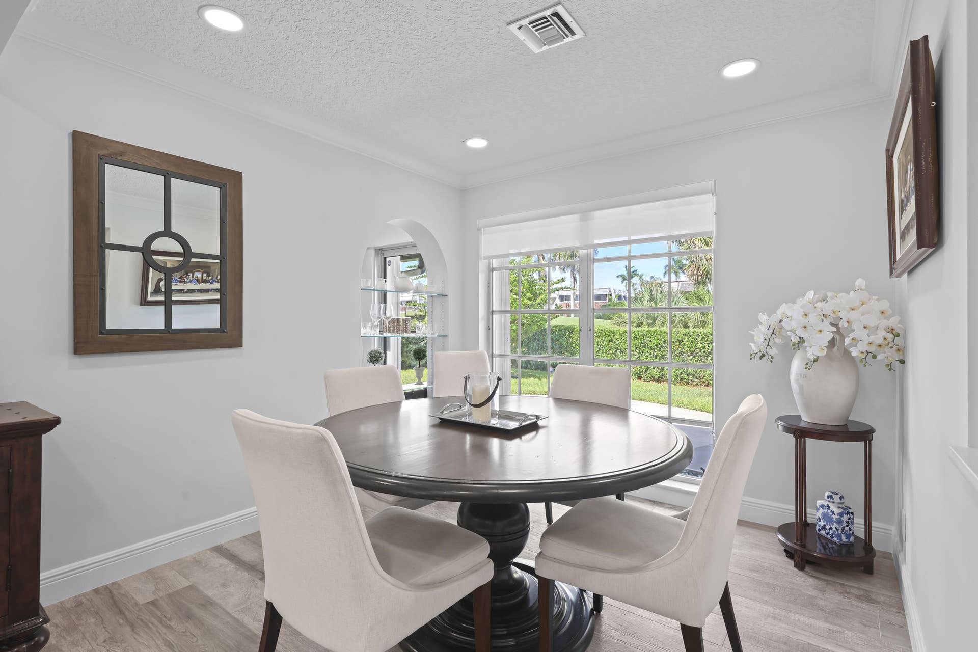 137 Clubhouse Boulevard, Atlantis, FL 33462 Dining area featuring wood-finish flooring, recessed lighting, a wide window with exterior landscape exposure, and a built-in arched display niche with glass shelving