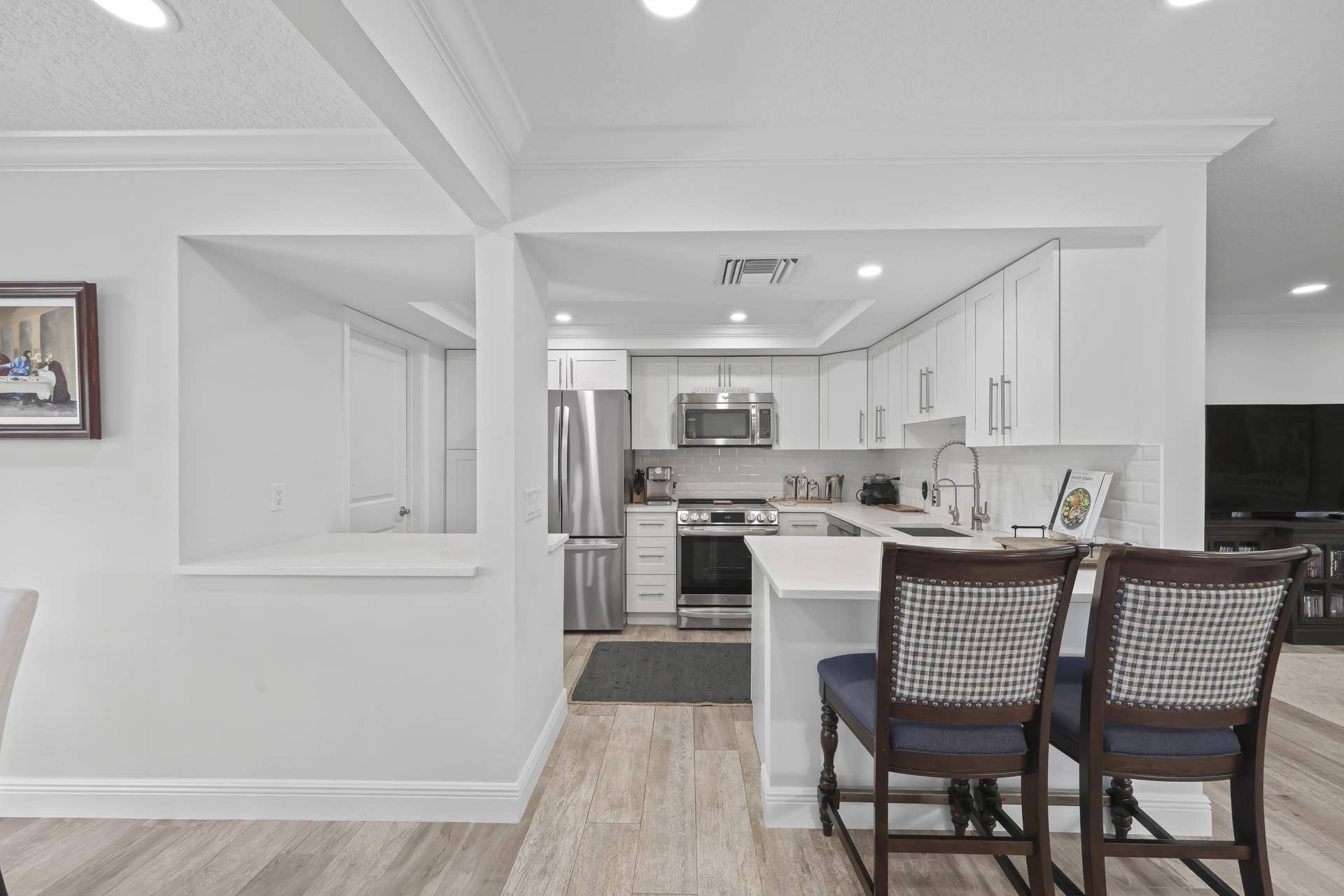 137 Clubhouse Boulevard, Atlantis, FL 33462 Kitchen featuring white shaker-style cabinetry, stainless steel appliances, white countertops, a subway tile backsplash, and wood-finish flooring
