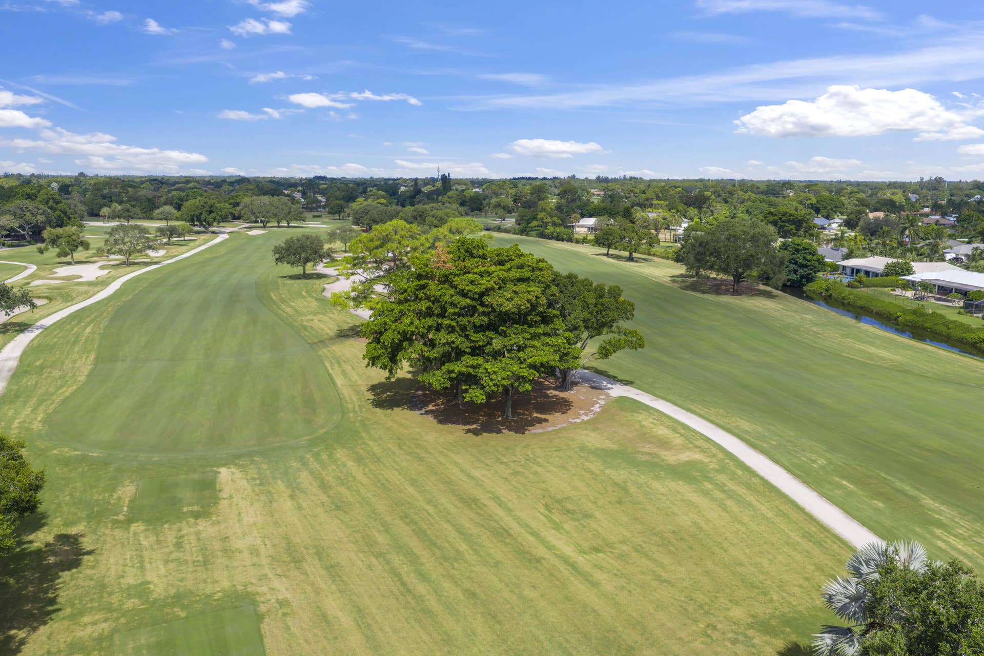 137 Clubhouse Boulevard, Atlantis, FL 33462 Aerial perspective of expansive golf course grounds featuring manicured fairways, mature canopy trees, concrete cart paths, and perimeter water frontage