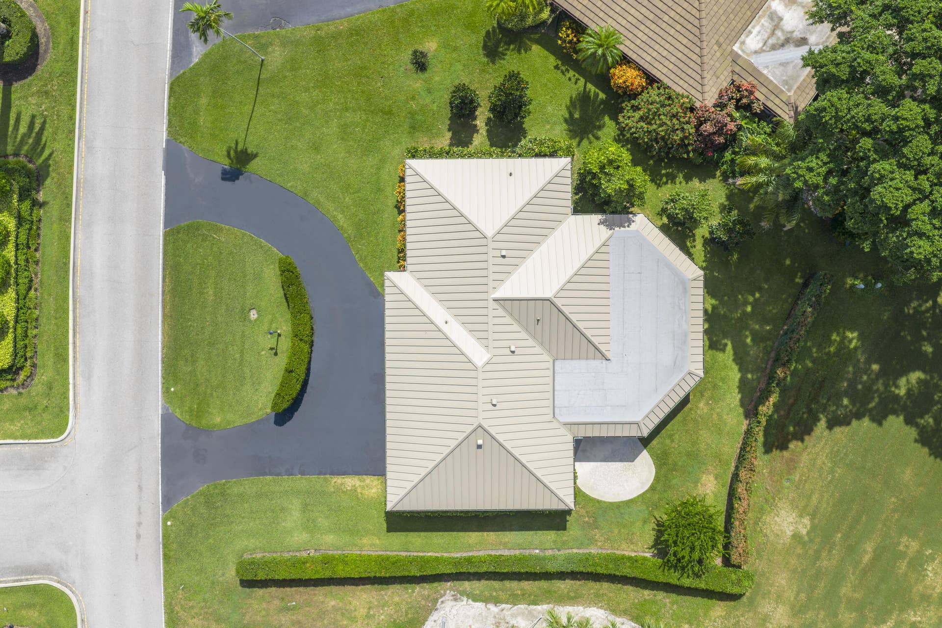 137 Clubhouse Boulevard, Atlantis, FL 33462 Aerial perspective of property featuring a metal roof, asphalt driveway, manicured landscaping, and mature trees