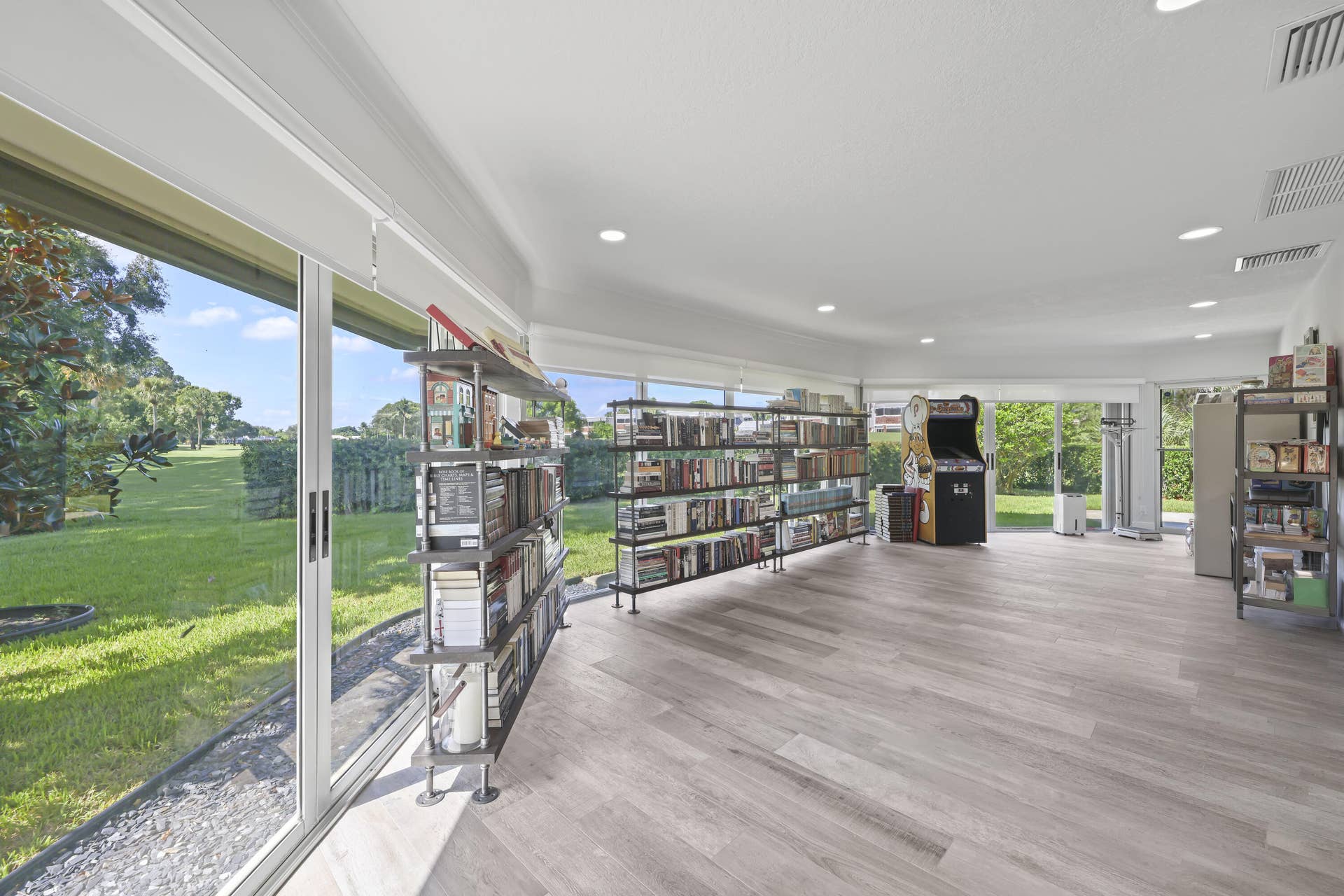 137 Clubhouse Boulevard, Atlantis, FL 33462 Expansive interior space featuring wood-finish flooring, recessed lighting, and wrap-around sliding glass doors providing exposure to the exterior grounds