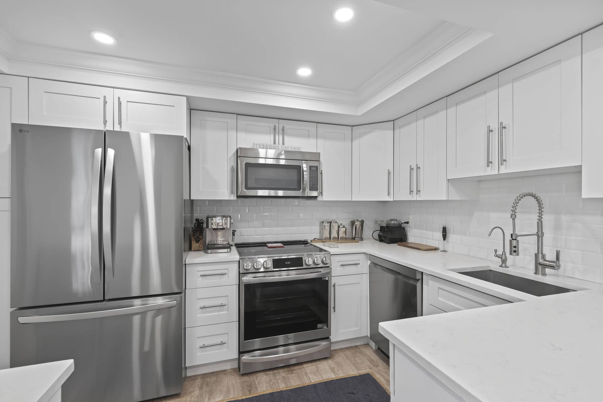 137 Clubhouse Boulevard, Atlantis, FL 33462 Kitchen featuring white Shaker-style cabinetry, white countertops, a subway tile backsplash, stainless steel appliances, and a gooseneck faucet