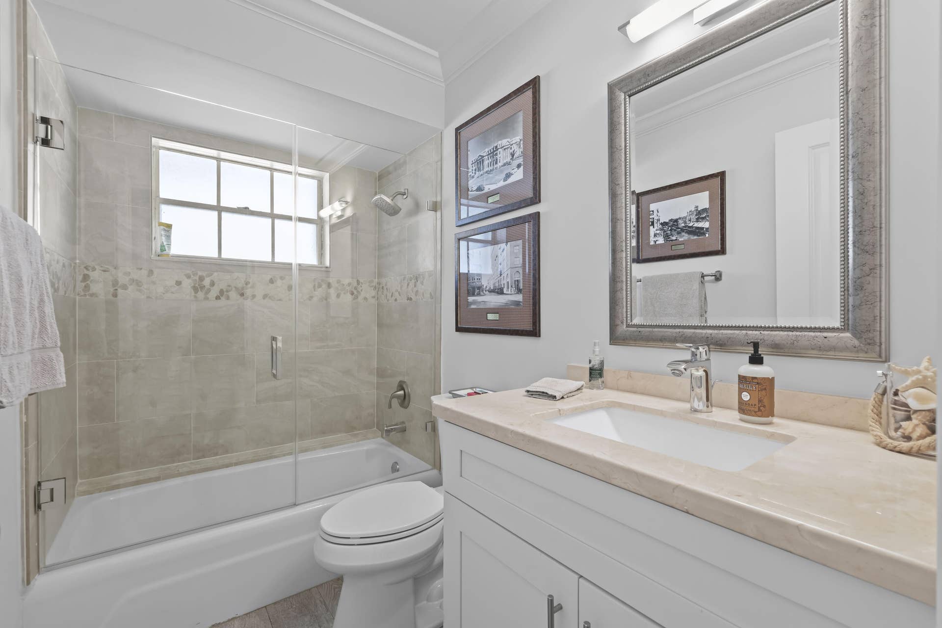 137 Clubhouse Boulevard, Atlantis, FL 33462 Bathroom featuring a white vanity with a stone countertop, an integrated rectangular sink, a shower-tub combination with a glass door enclosure, and a wall-mounted mirror