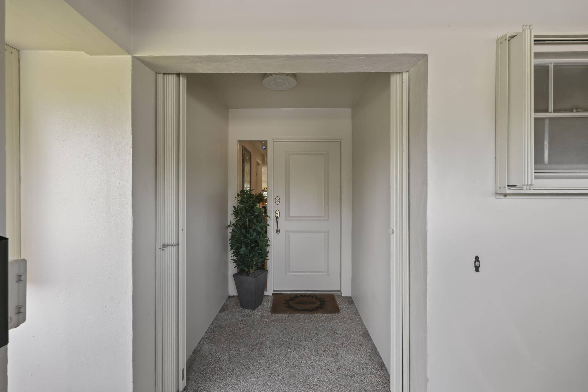 137 Clubhouse Boulevard, Atlantis, FL 33462 Covered entry featuring a paneled door, sidelight, flush-mount ceiling light, and textured concrete flooring
