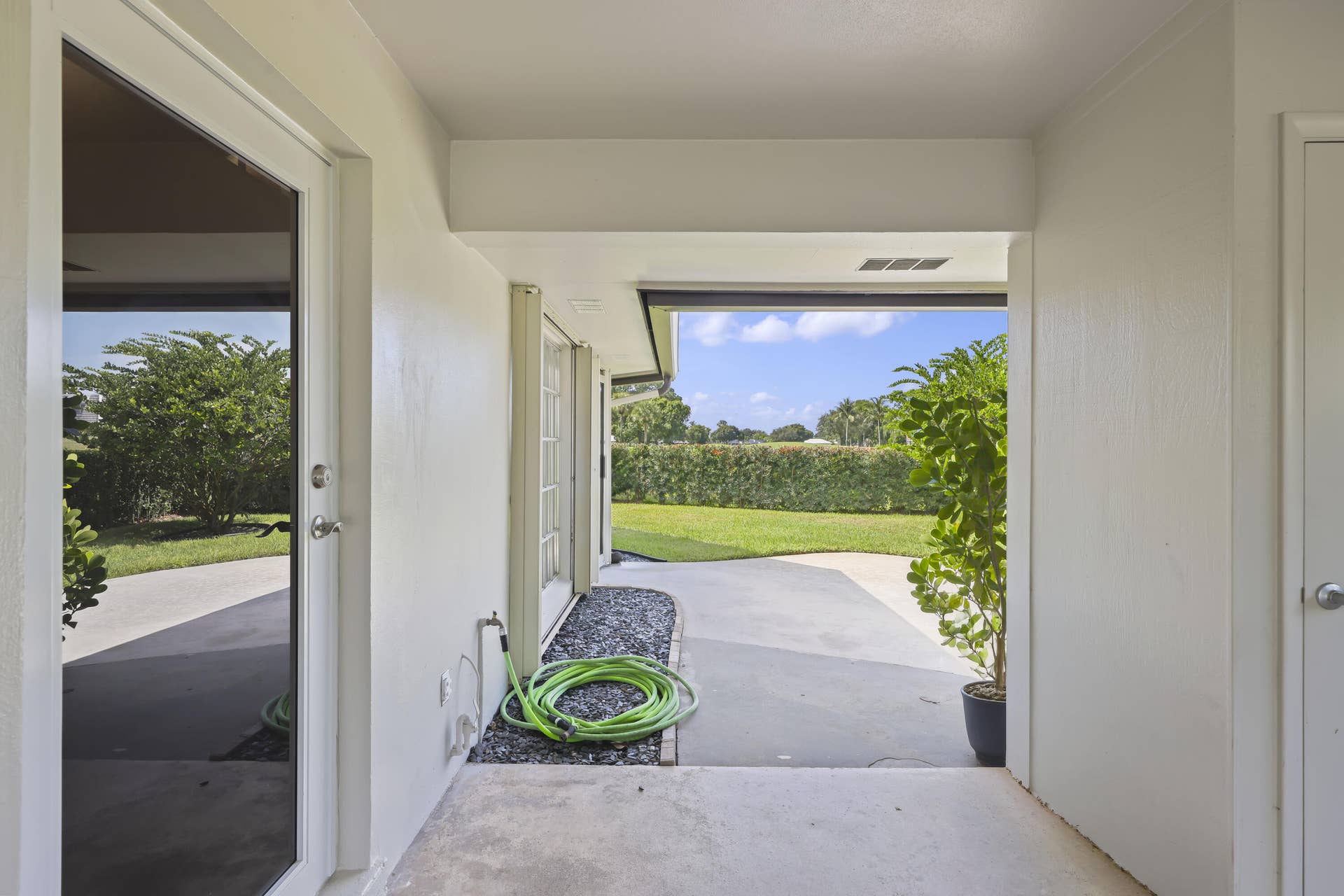 137 Clubhouse Boulevard, Atlantis, FL 33462 Covered patio featuring concrete flooring, external water spigot, and clear glass-pane door