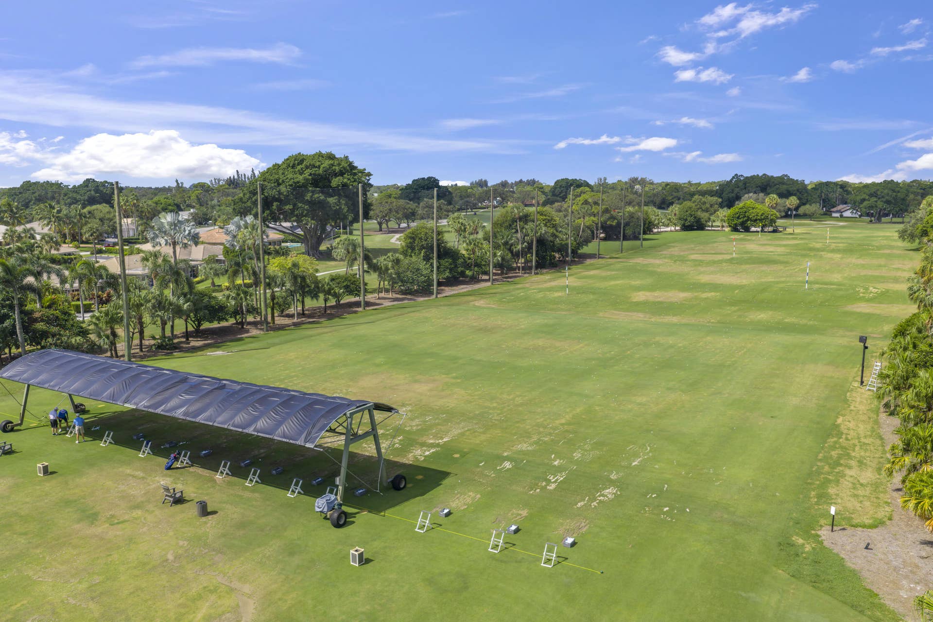 137 Clubhouse Boulevard, Atlantis, FL 33462 Expansive golf driving range featuring a covered hitting structure, multiple hitting bays, maintained turf, and perimeter landscaping with mature trees