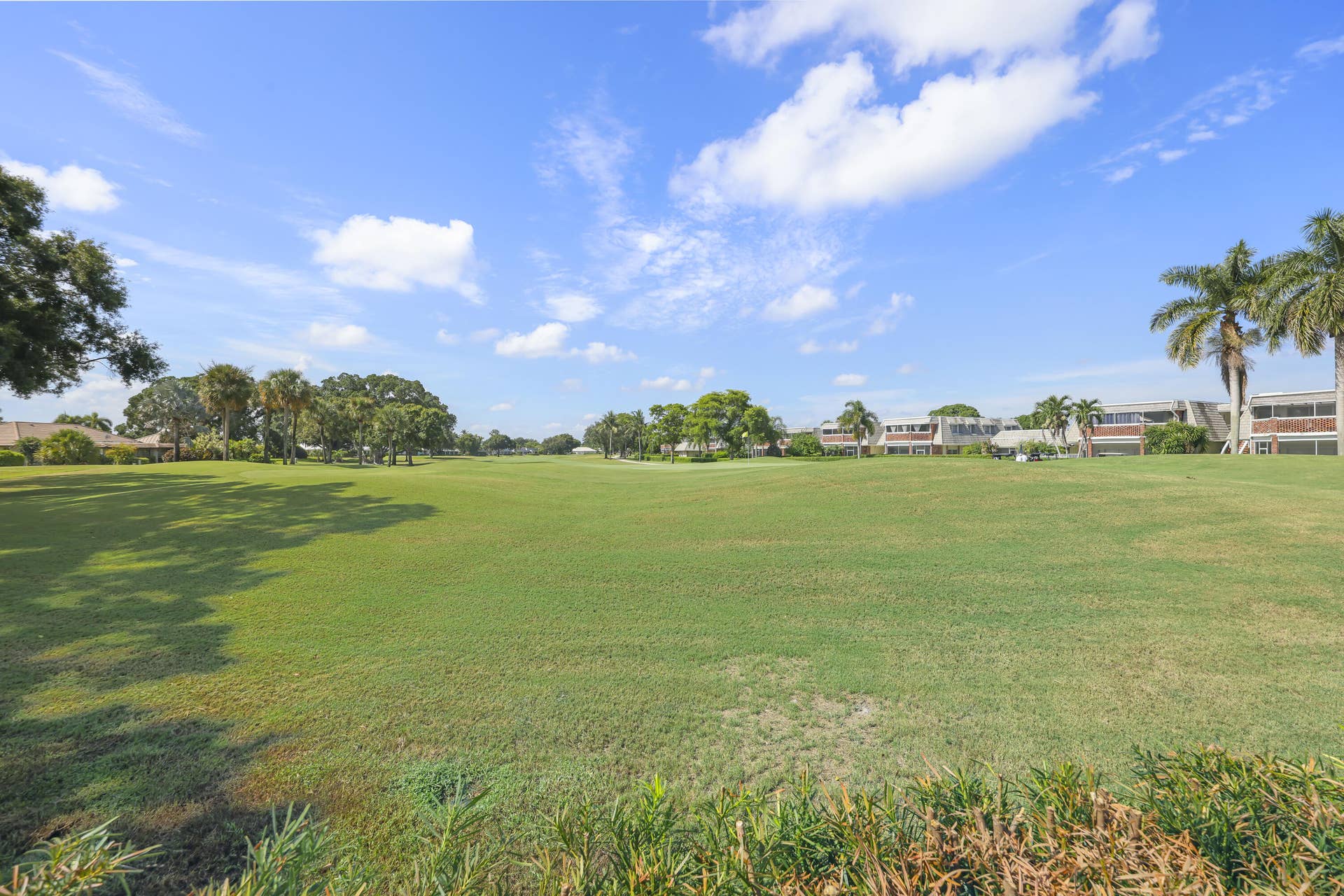 137 Clubhouse Boulevard, Atlantis, FL 33462 Expansive lawn featuring mature trees and established perimeter landscaping