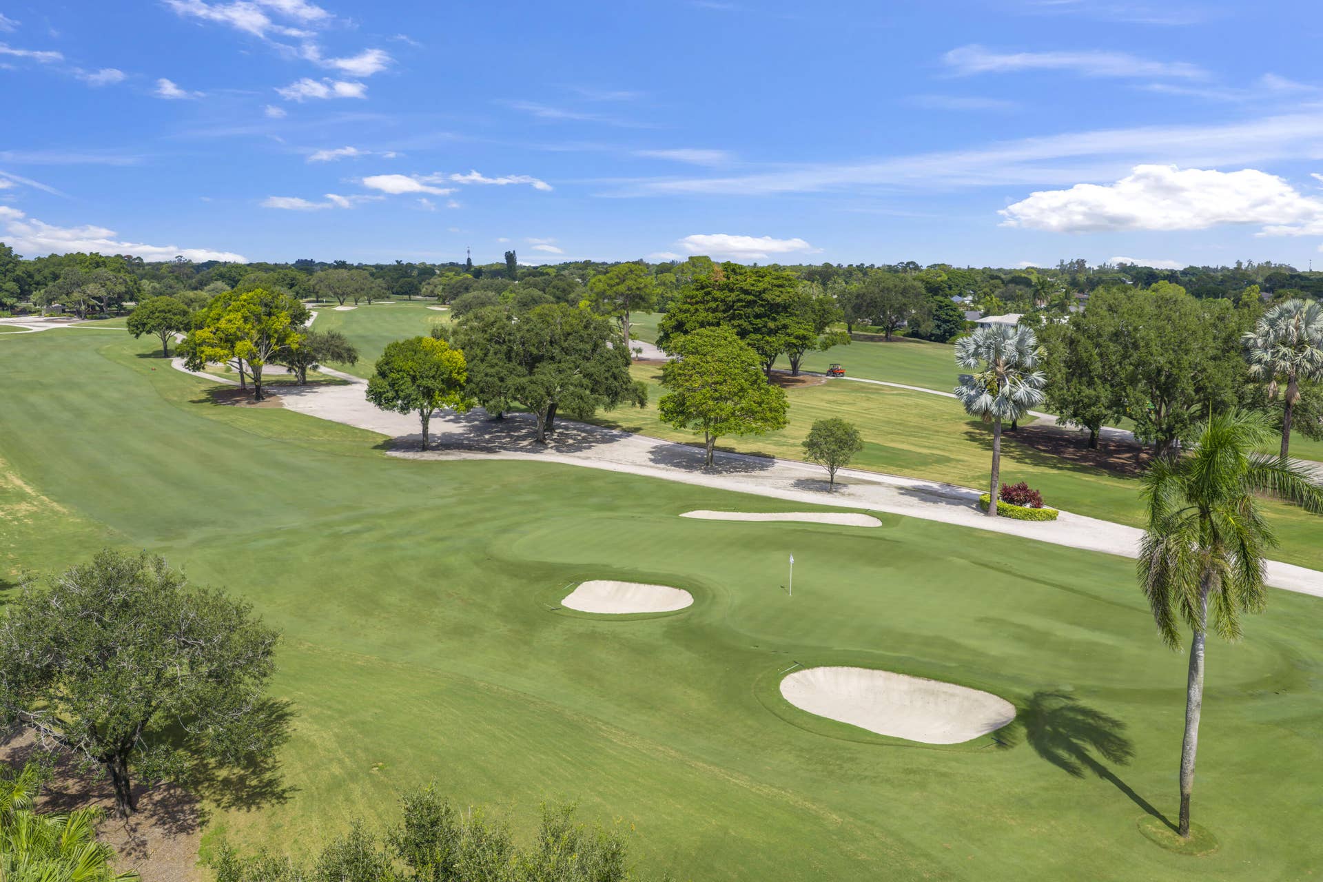137 Clubhouse Boulevard, Atlantis, FL 33462 Expansive golf course grounds featuring multiple sand bunkers, manicured fairways, mature canopy trees, and ornamental palms
