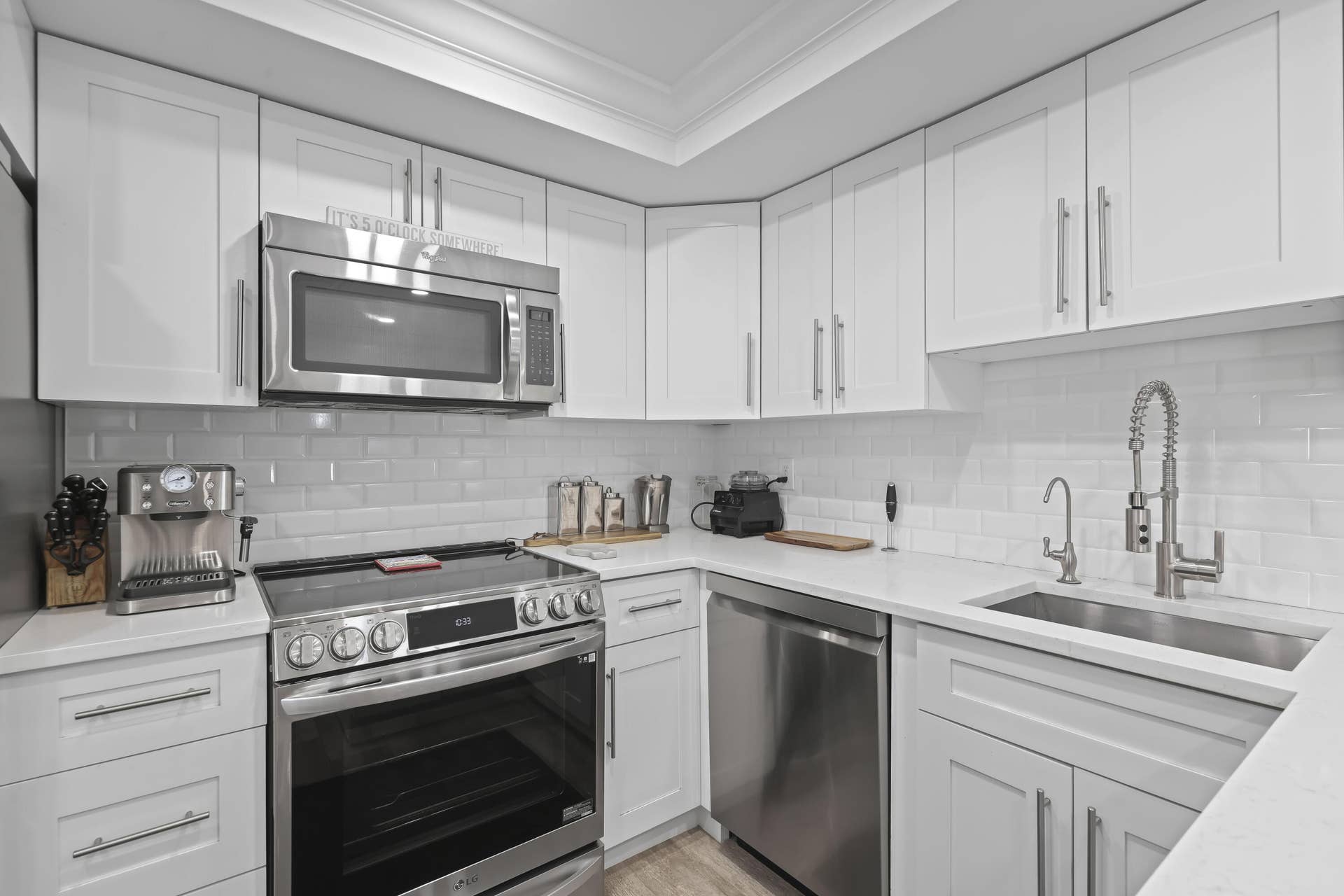 137 Clubhouse Boulevard, Atlantis, FL 33462 Kitchen featuring white shaker-style cabinetry, quartz countertops, white subway tile backsplash, stainless steel appliances, and a gooseneck faucet