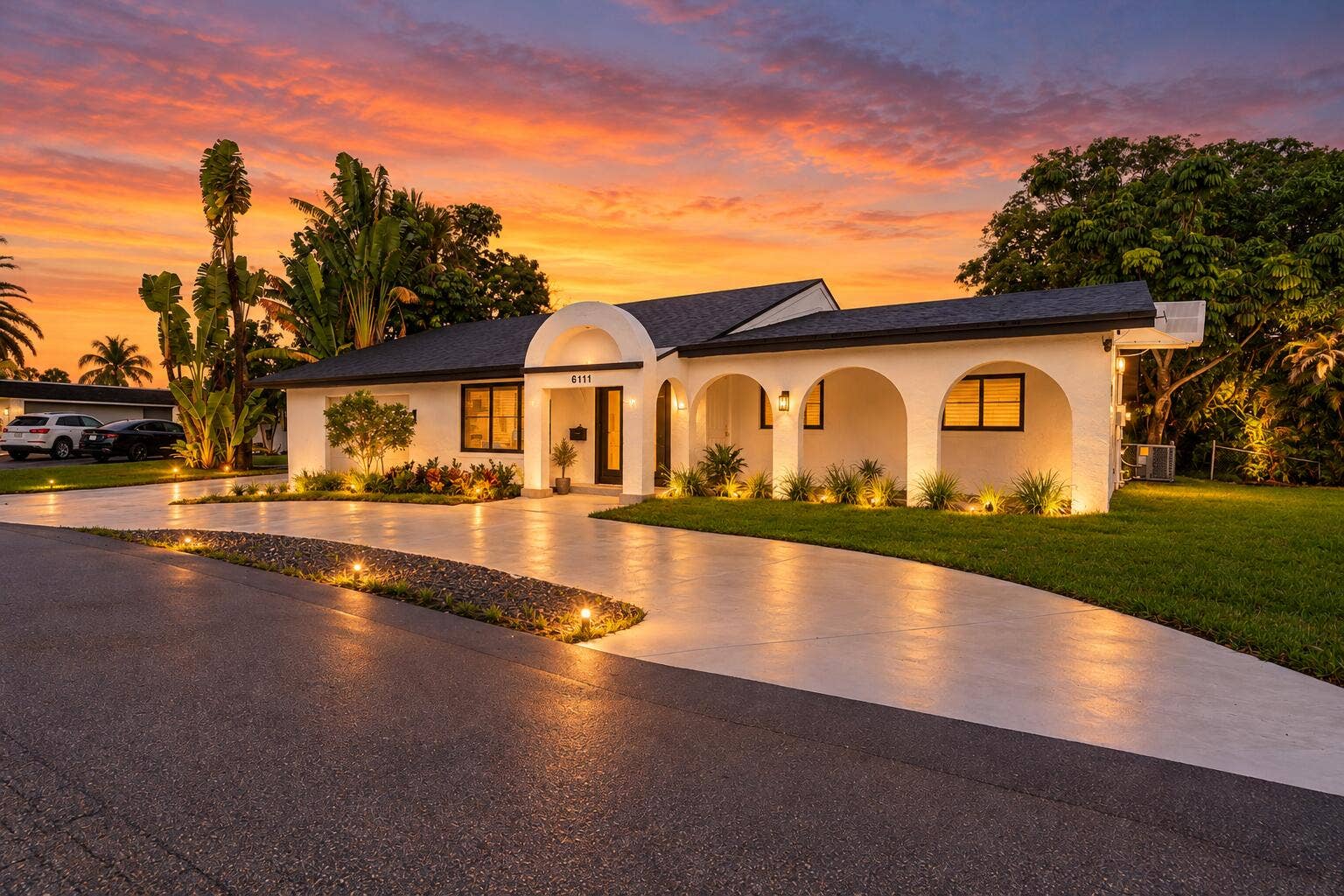 6111 WHITE OAK Lane, Tamarac, FL 33319 Single-story exterior featuring a rounded arched portico, stucco facade, expansive concrete driveway, and manicured lawn