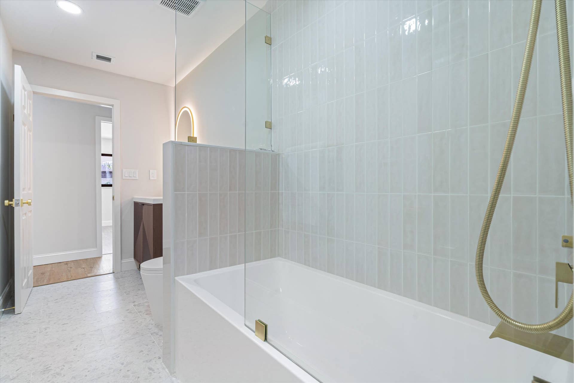 6111 WHITE OAK Lane, Tamarac, FL 33319 Bathroom featuring a glass-enclosed soaking tub with vertical tile surround, gold-tone hardware, and a vanity cabinet