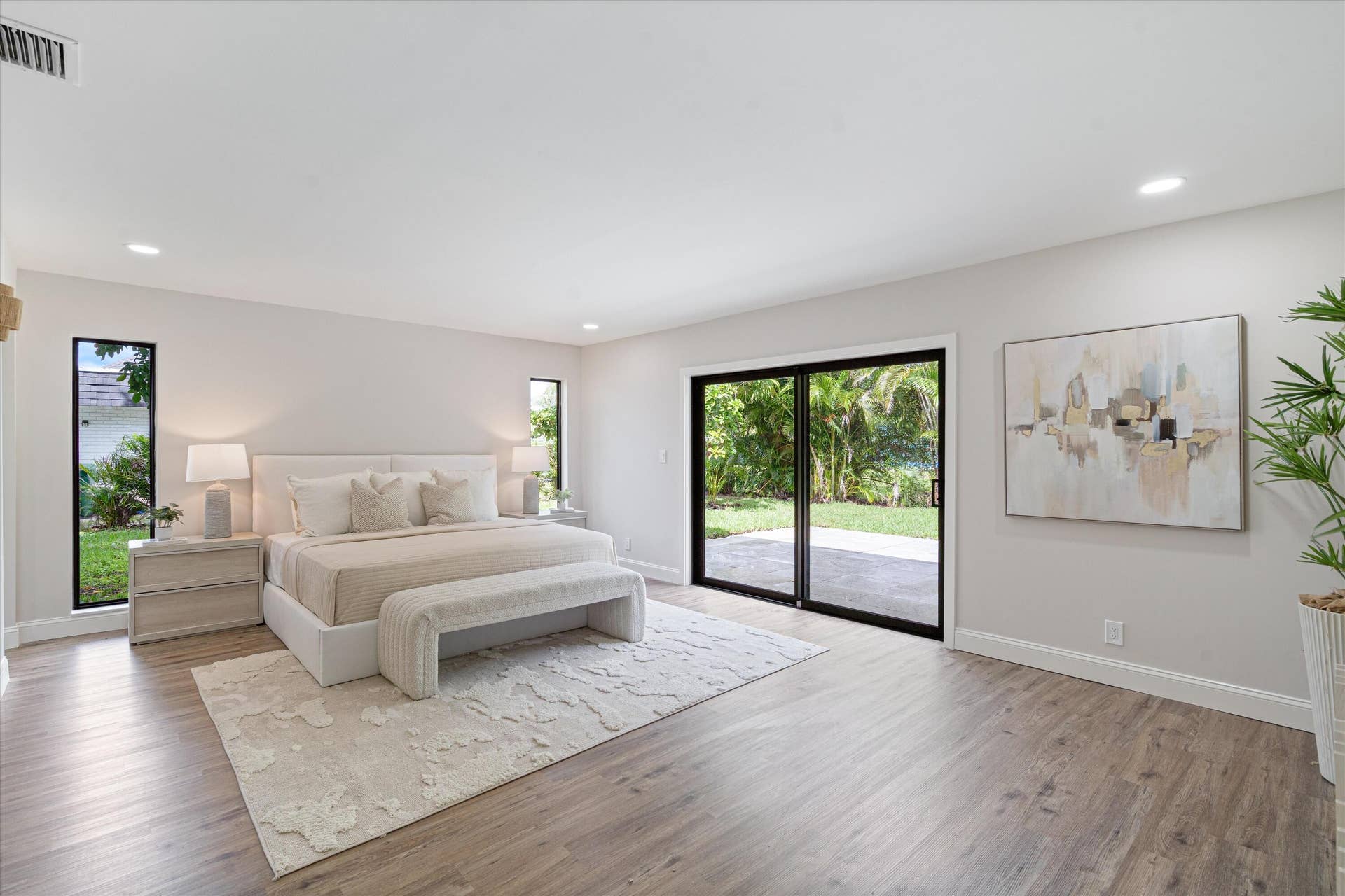 6111 WHITE OAK Lane, Tamarac, FL 33319 Spacious room with wood-finish flooring, recessed lighting, vertical windows, and black-framed sliding glass doors opening to the exterior