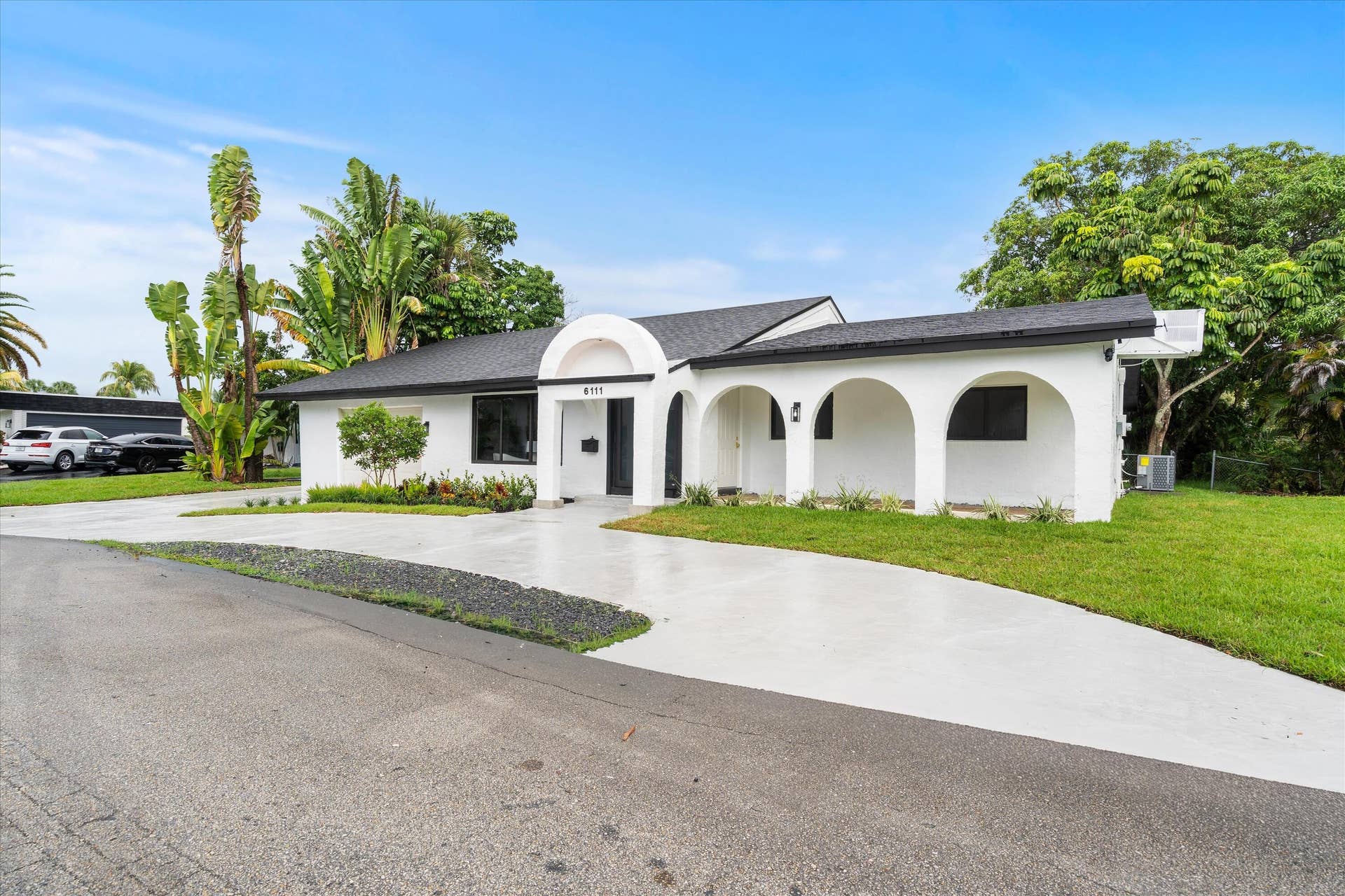 6111 WHITE OAK Lane, Tamarac, FL 33319 Single-story exterior featuring a white stucco facade, arched covered entryway, multi-arch colonnade, and a concrete driveway