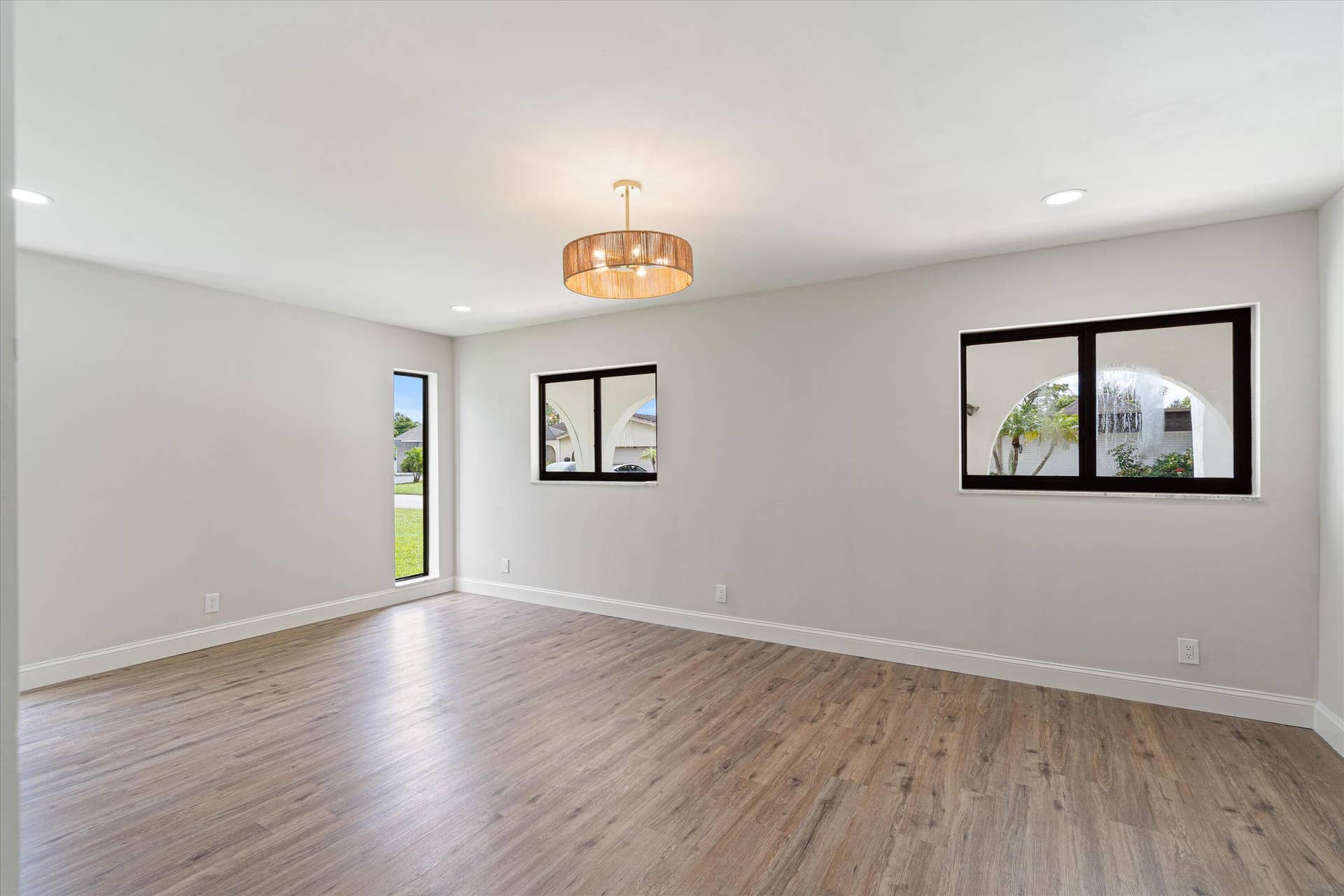 6111 WHITE OAK Lane, Tamarac, FL 33319 Neutral interior space featuring wood-finish flooring, recessed lighting, a drum chandelier, and black-framed windows