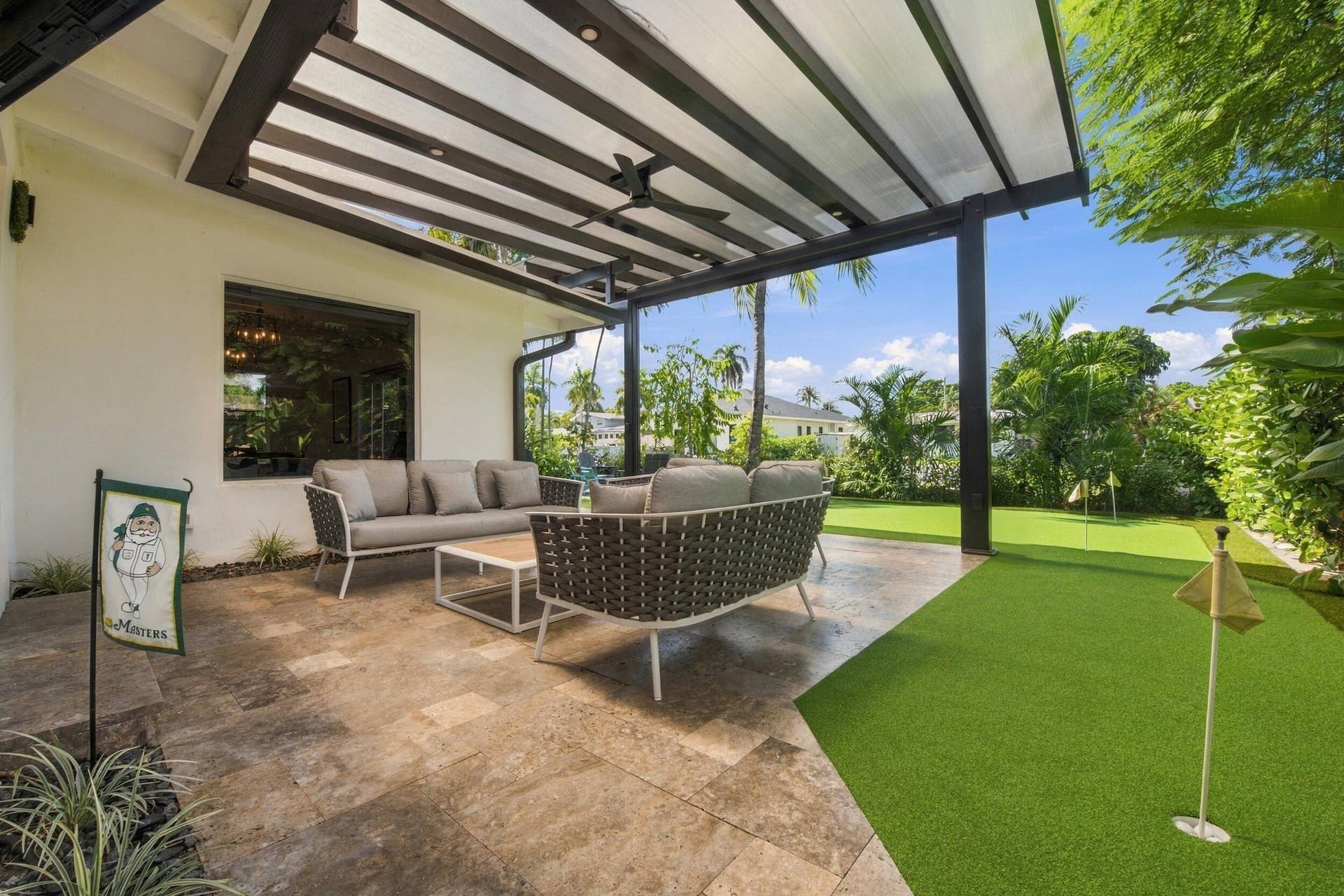 2449 KEY LARGO Lane, Fort Lauderdale, FL 33312 Covered patio with stone-tile flooring, metal pergola, integrated ceiling fan, and backyard putting green