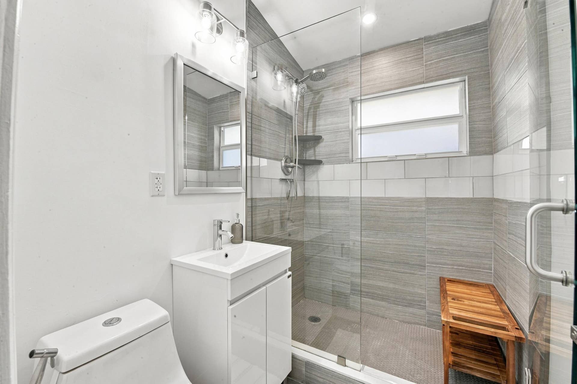 2449 KEY LARGO Lane, Fort Lauderdale, FL 33312 Bathroom featuring a glass-enclosed walk-in shower with horizontal tile surround, wall-mounted light fixtures, a vanity with an integrated basin, and an inset medicine cabinet