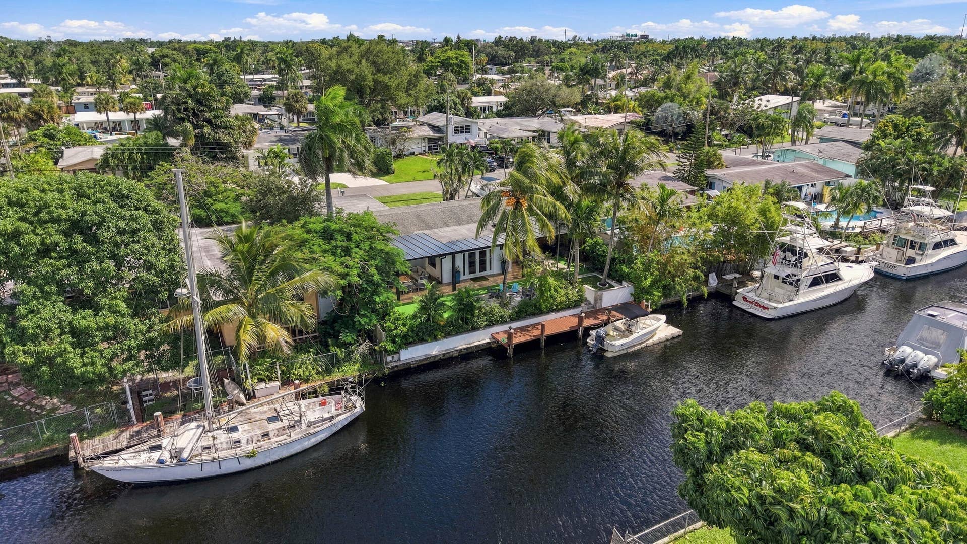 2449 KEY LARGO Lane, Fort Lauderdale, FL 33312 Waterfront property featuring a private boat dock, concrete bulkhead, mature palm trees, and established landscaping