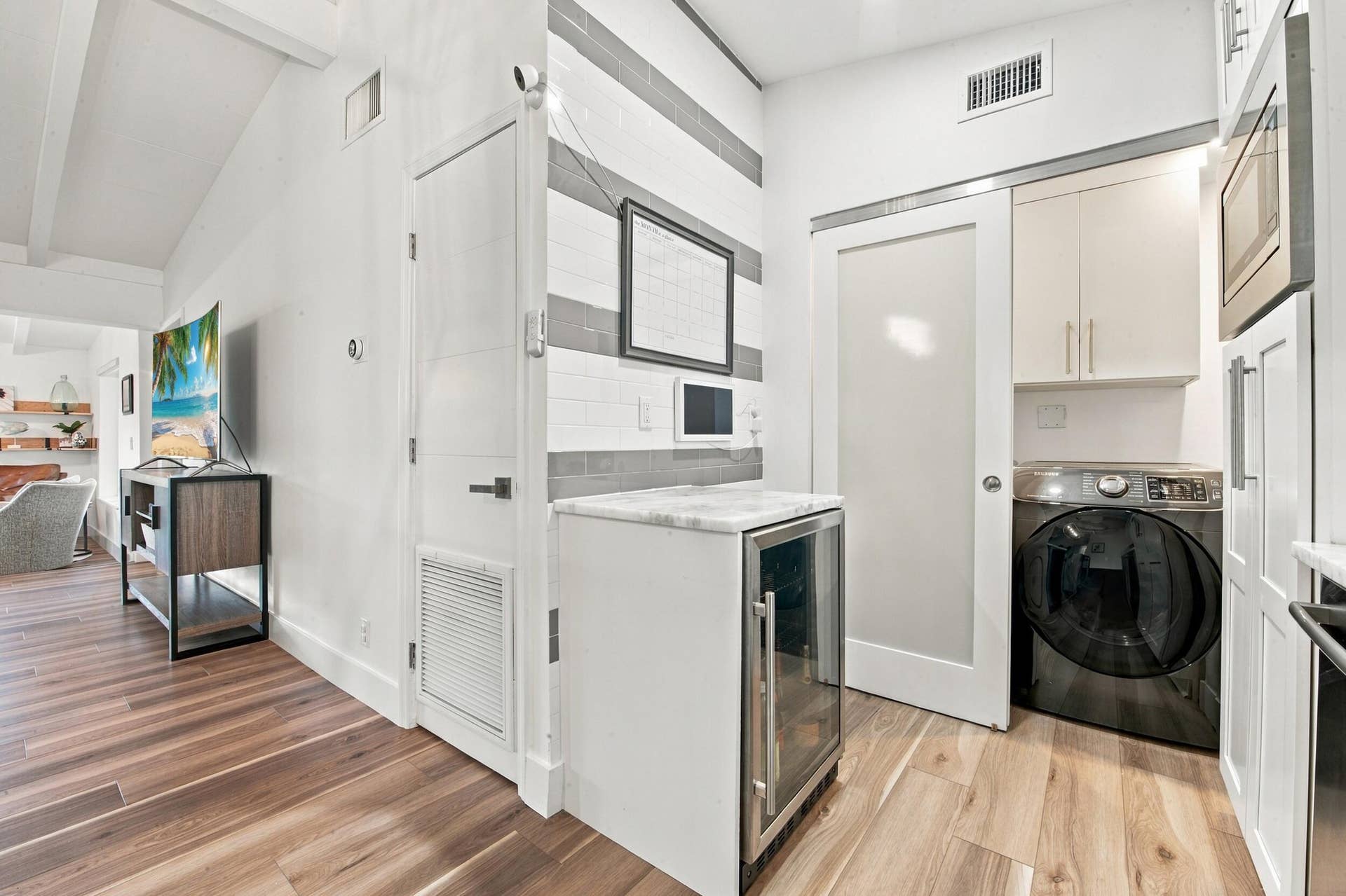 2449 KEY LARGO Lane, Fort Lauderdale, FL 33312 Utility space featuring wood-finish flooring, a built-in wine refrigerator with a stone countertop, a tiled accent wall, and a sliding door with a glass panel