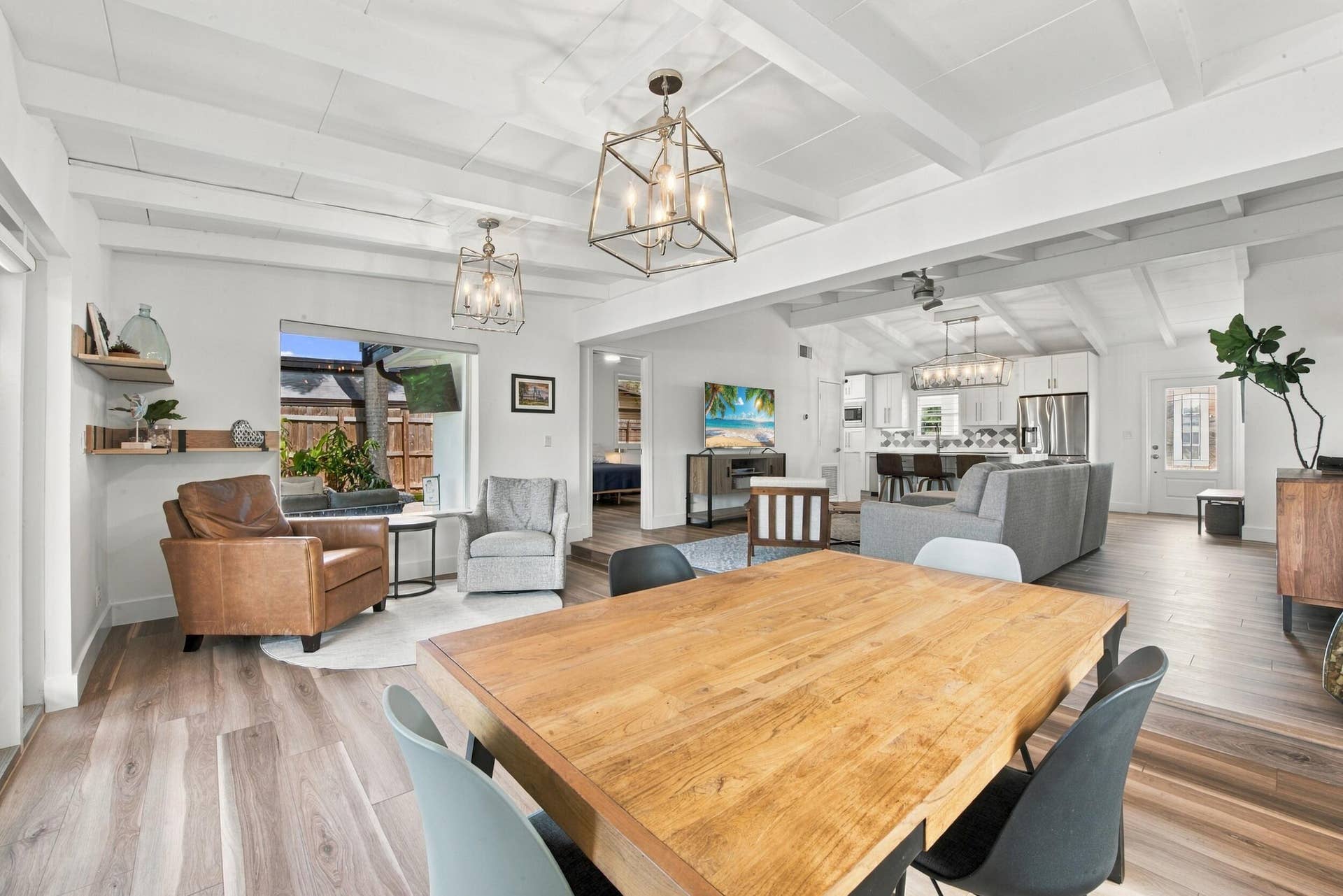 2449 KEY LARGO Lane, Fort Lauderdale, FL 33312 Open-concept interior featuring wood-finish flooring, exposed ceiling beams, custom wall-mounted shelving, and geometric lantern-style light fixtures