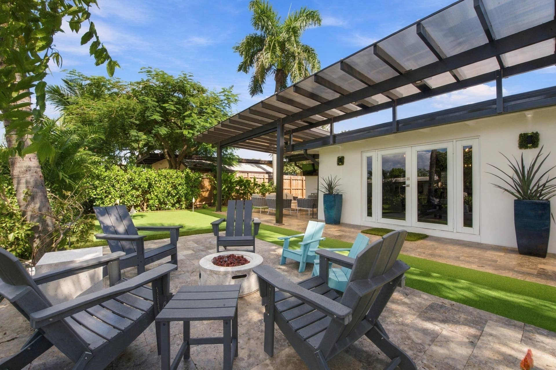 2449 KEY LARGO Lane, Fort Lauderdale, FL 33312 Outdoor patio featuring stone tile flooring, a metal-framed overhead trellis, synthetic turf accents, and white French doors