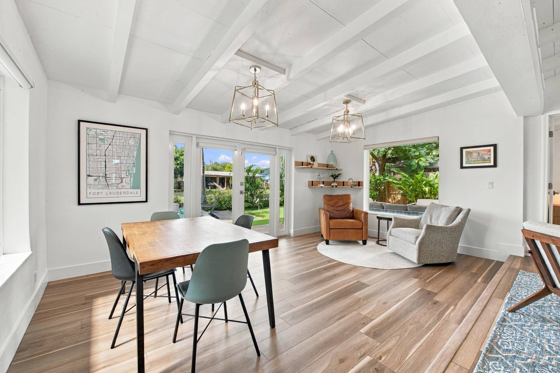 2449 KEY LARGO Lane, Fort Lauderdale, FL 33312 Exposed beam vaulted ceiling, wood-finish flooring, dual geometric metal chandeliers, glass-paneled double doors, and built-in floating wall shelving