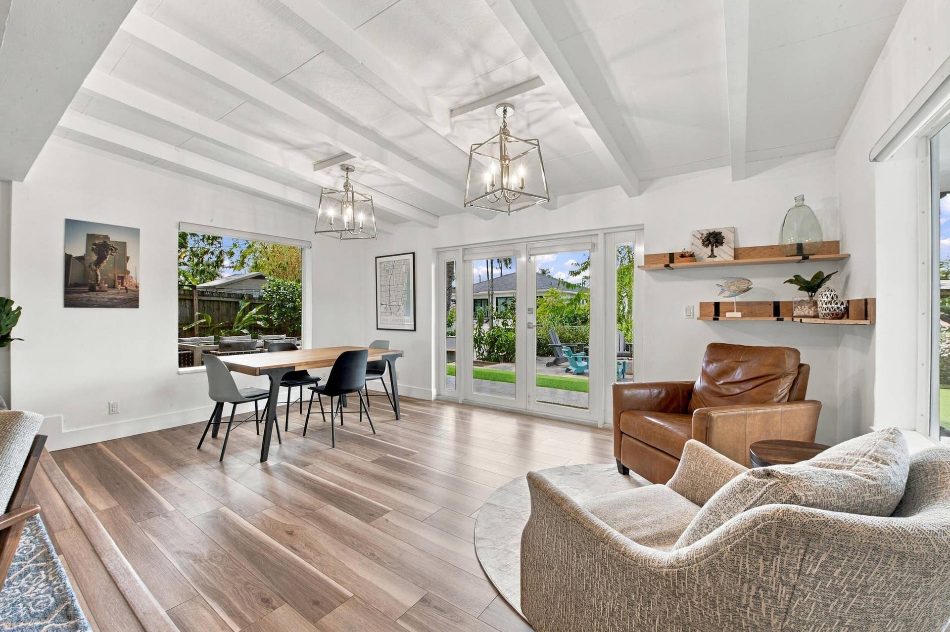 2449 KEY LARGO Lane, Fort Lauderdale, FL 33312 Vaulted ceilings with exposed beams, wood-finish flooring, two metal lantern-style pendant fixtures, glass-paned double doors, and built-in floating wall shelving