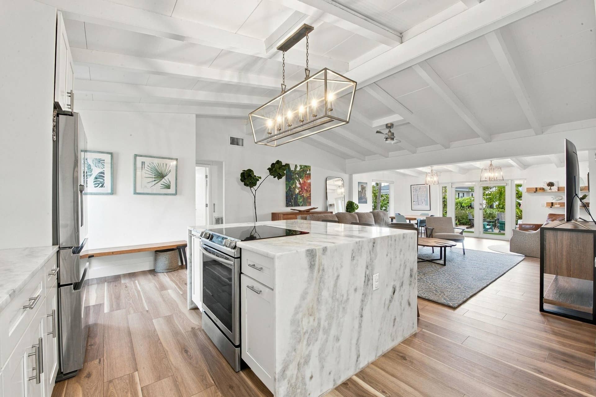 2449 KEY LARGO Lane, Fort Lauderdale, FL 33312 Kitchen featuring a stone-topped waterfall island, stainless steel range, wood-finish flooring, vaulted ceilings with exposed beams, and a geometric linear pendant light