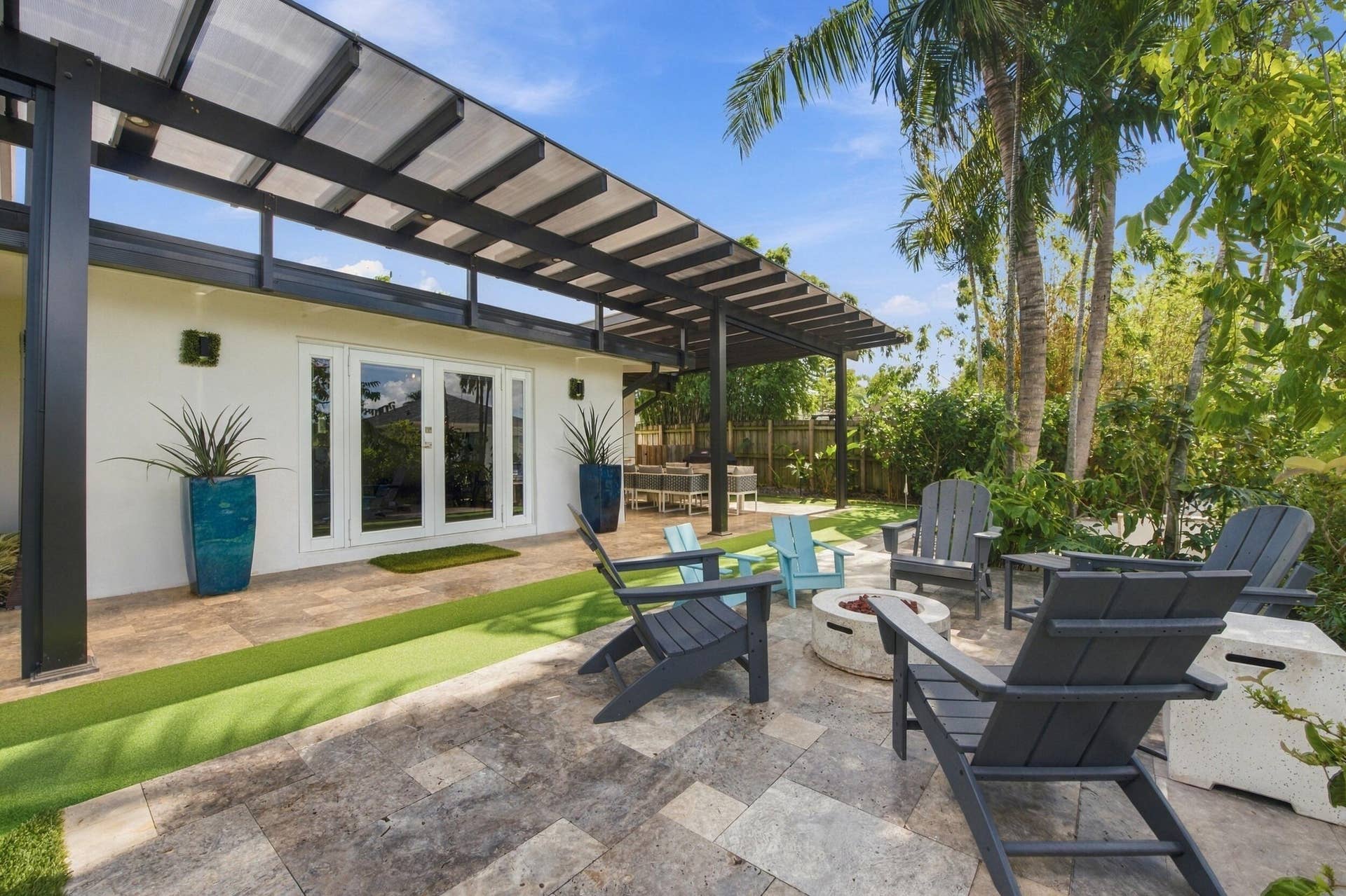 2449 KEY LARGO Lane, Fort Lauderdale, FL 33312 Outdoor patio featuring stone tile hardscaping, an expansive black metal pergola, and synthetic turf accent surfacing