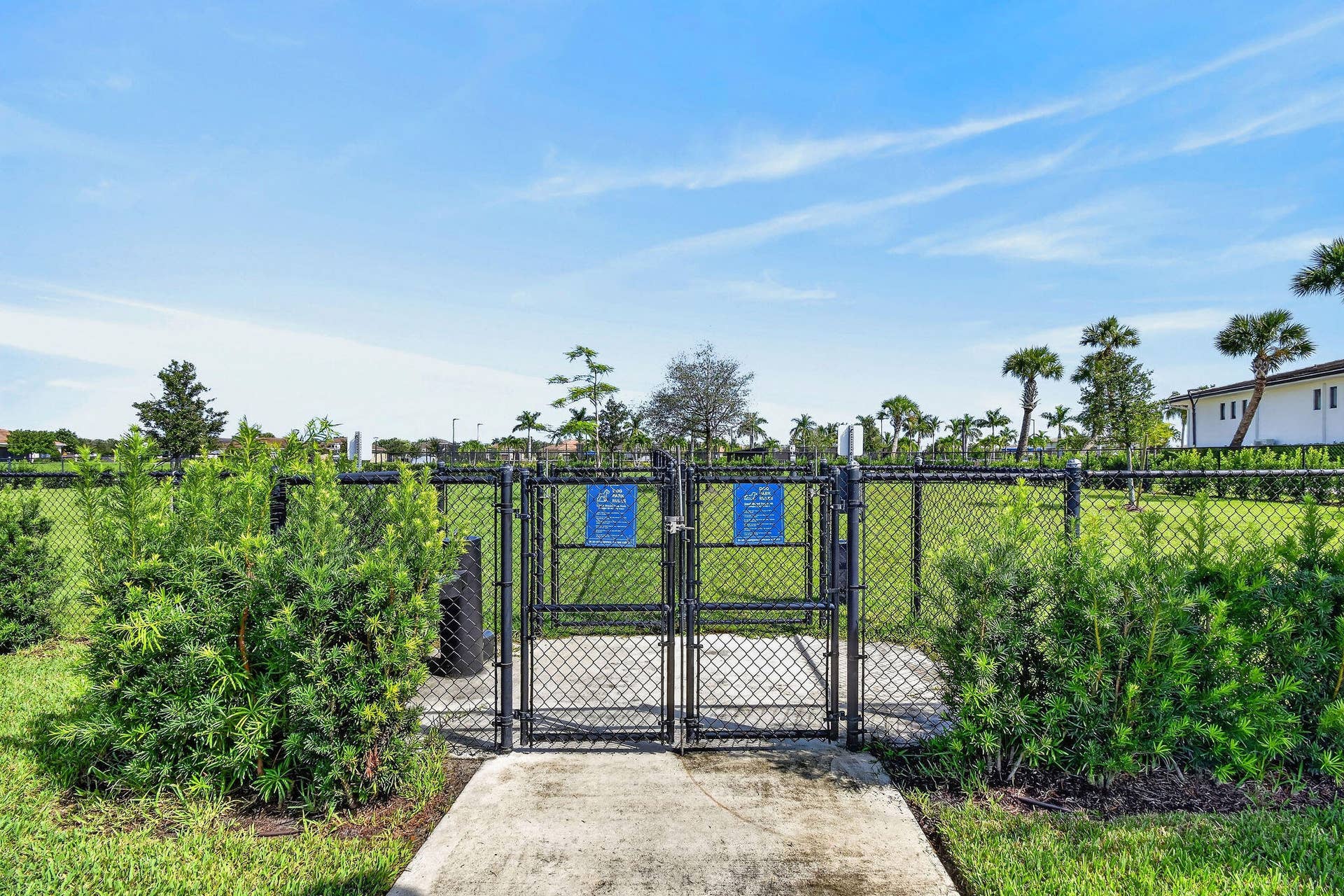 15811 Key Biscayne Lane, Westlake, FL 33470 Fenced recreational area with a chain-link perimeter, established landscaping, and a concrete pathway