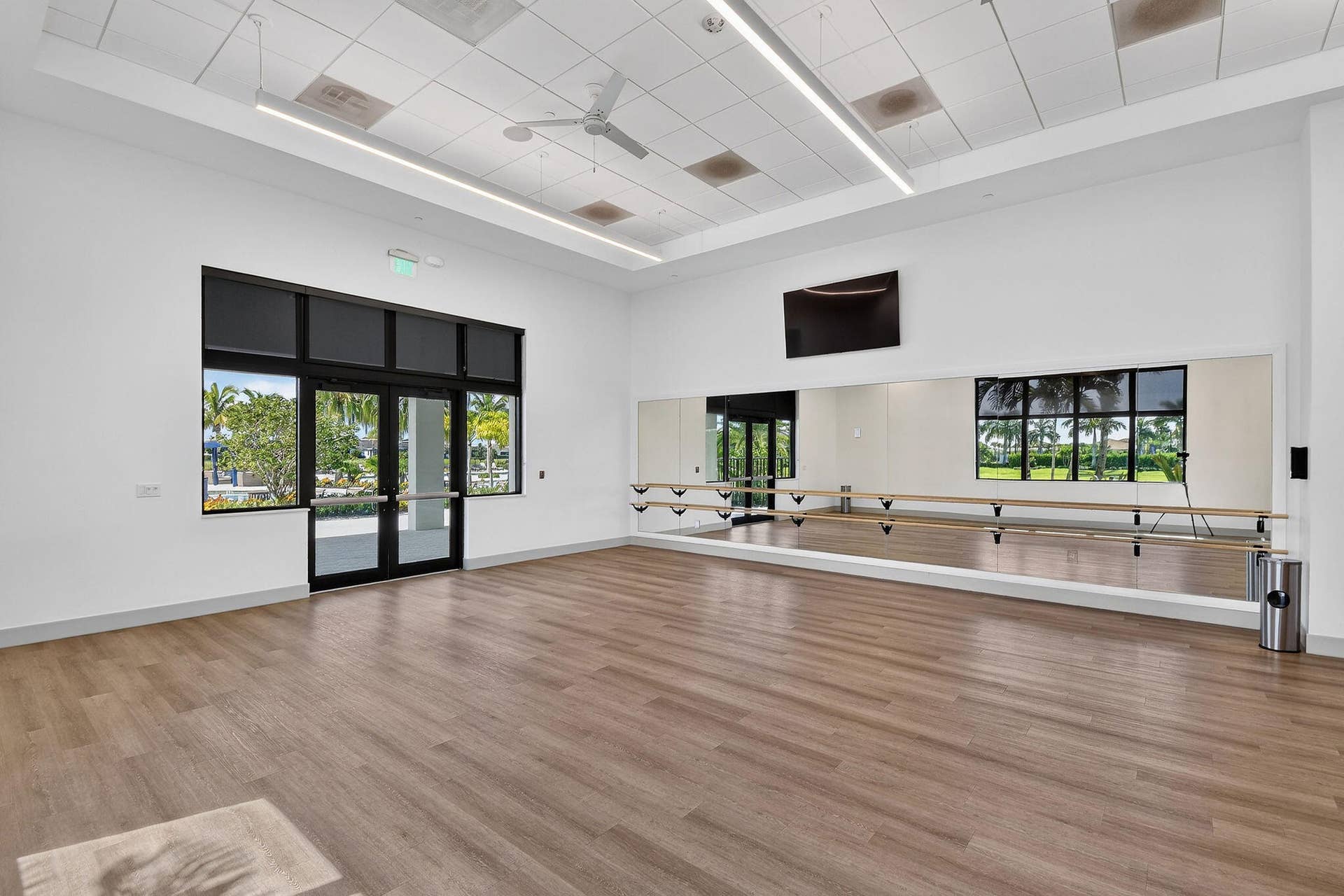 15811 Key Biscayne Lane, Westlake, FL 33470 Spacious room featuring wood-finish flooring, full-wall mirrors with ballet barres, a ceiling fan, and large windows with exterior access