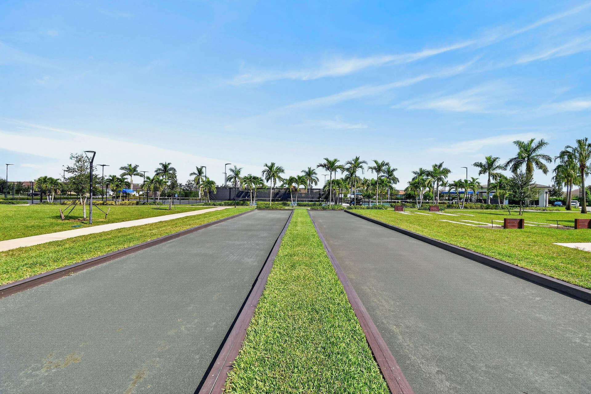 15811 Key Biscayne Lane, Westlake, FL 33470 Bocce ball court with dark gray surfacing, bordered by green grass and concrete pathways