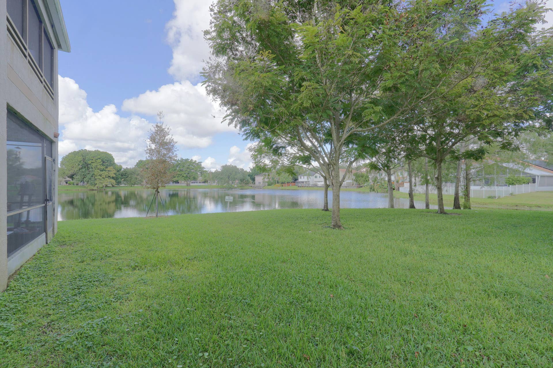 9853 NW 3RD Court, #7, Plantation, FL 33324 Waterfront lot featuring a screened-in lanai, mature trees, and an expansive lawn
