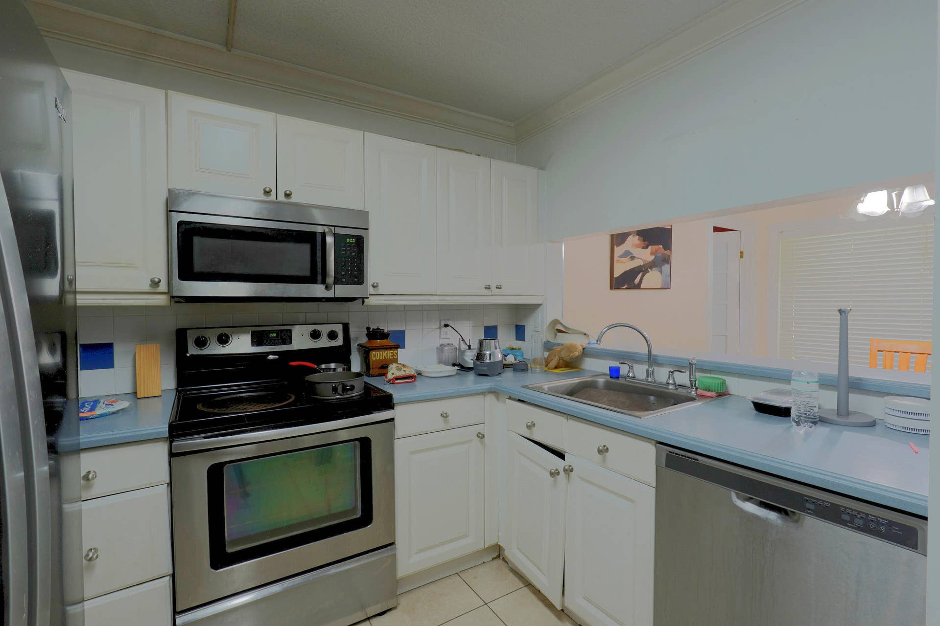 9853 NW 3RD Court, #7, Plantation, FL 33324 Kitchen featuring white shaker-style cabinetry, stainless steel appliances, solid-surface countertops, and a stainless steel sink with a goose-neck faucet