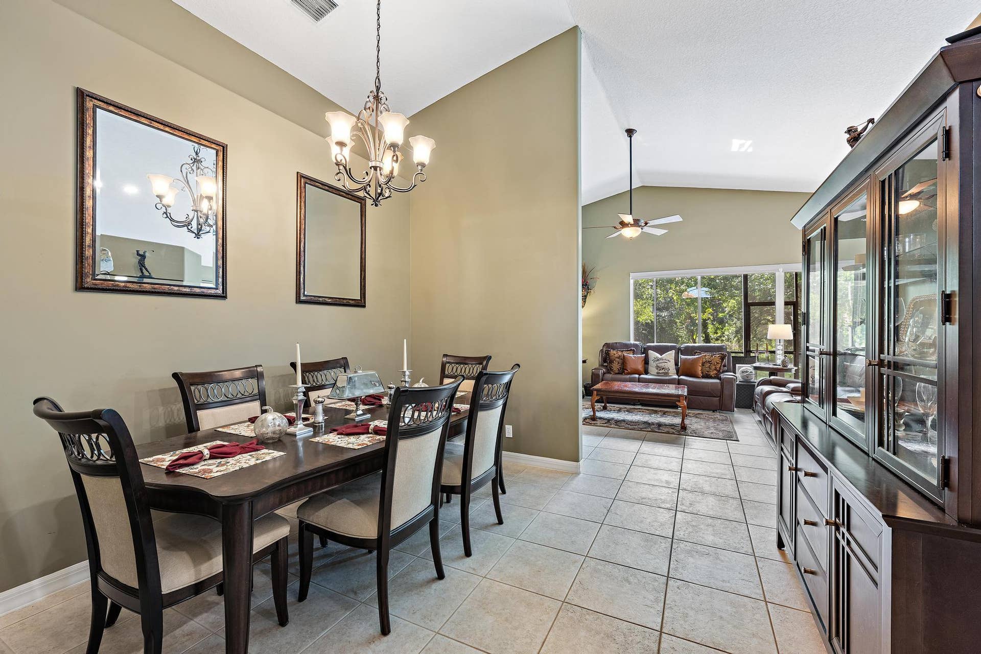 Dining area featuring vaulted ceilings, oversized ceramic tile flooring, and a decorative chandelier