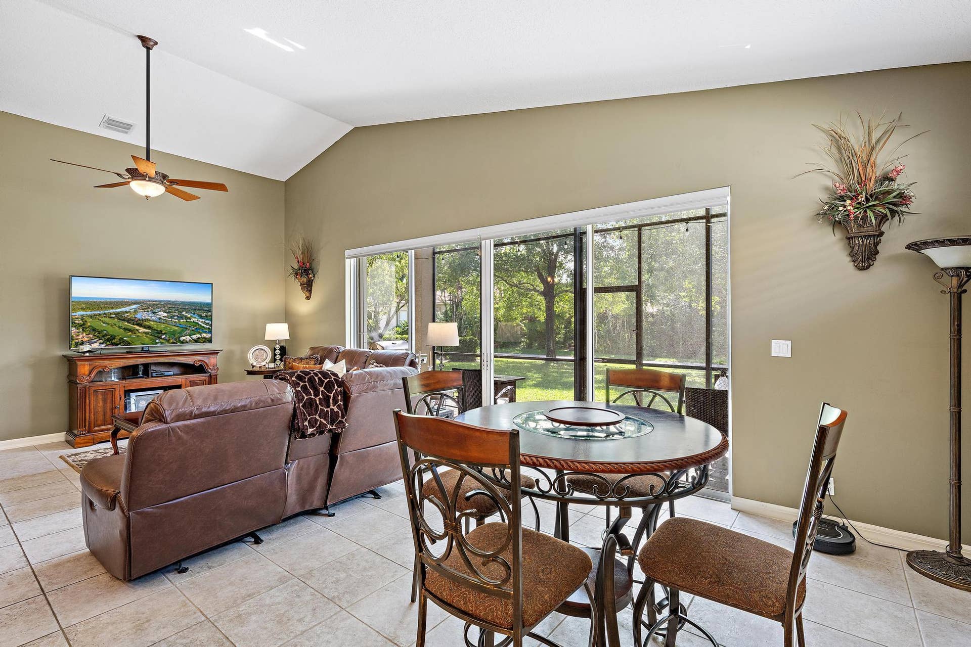 Vaulted ceilings, large-format tile flooring, and oversized sliding glass doors with custom remote controlled blinds opening to a screened lanai