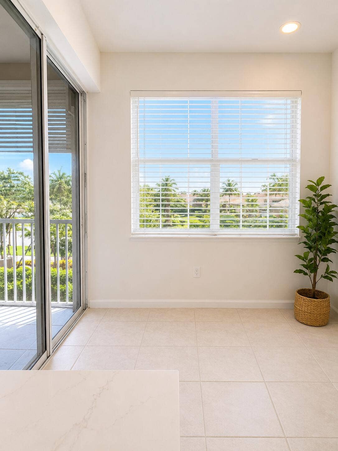Neutral-toned tile flooring, recessed ceiling lighting, sliding glass door, and large picture window