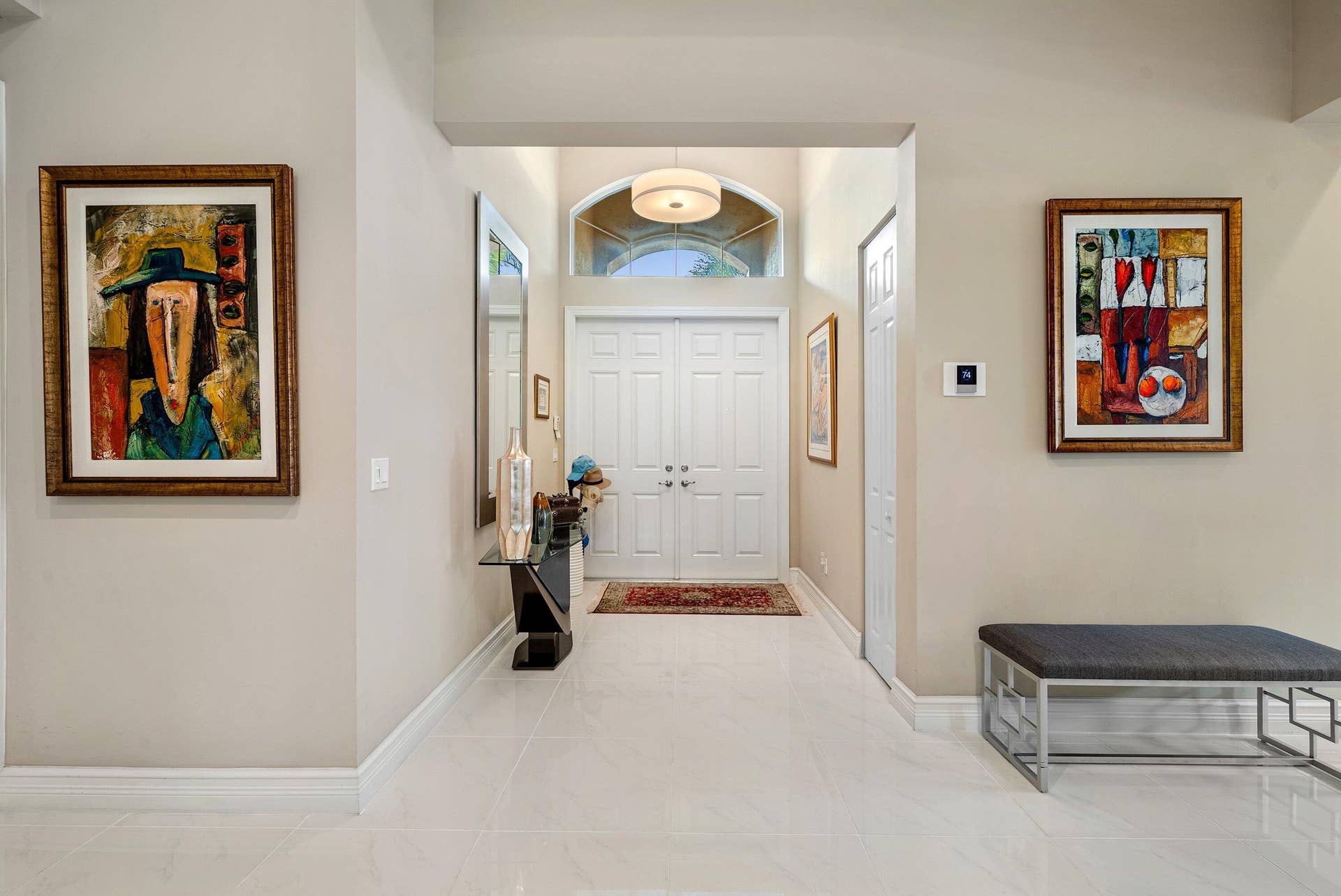 Foyer featuring double-door entry, arched transom window, pendant lighting, and polished stone-finish flooring