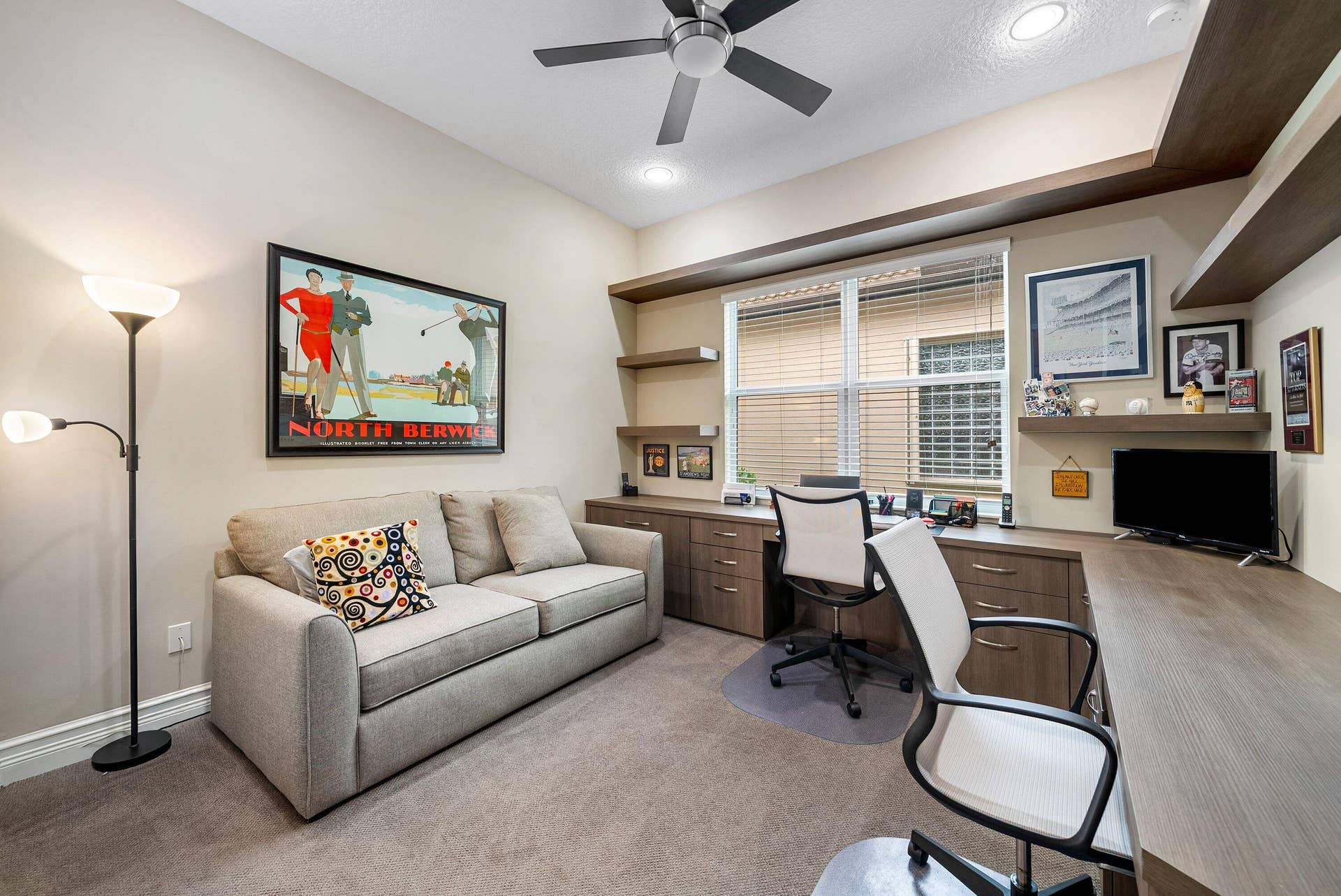 Built-in wood-finish cabinetry, integrated desk workspace, floating shelving, ceiling fan with light fixture, and recessed lighting