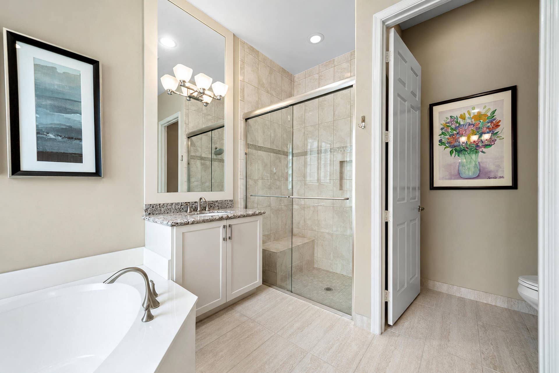 Bathroom featuring a walk-in shower with a glass enclosure and built-in bench, a soaking tub, a vanity with stone-finish countertop, and tiled flooring