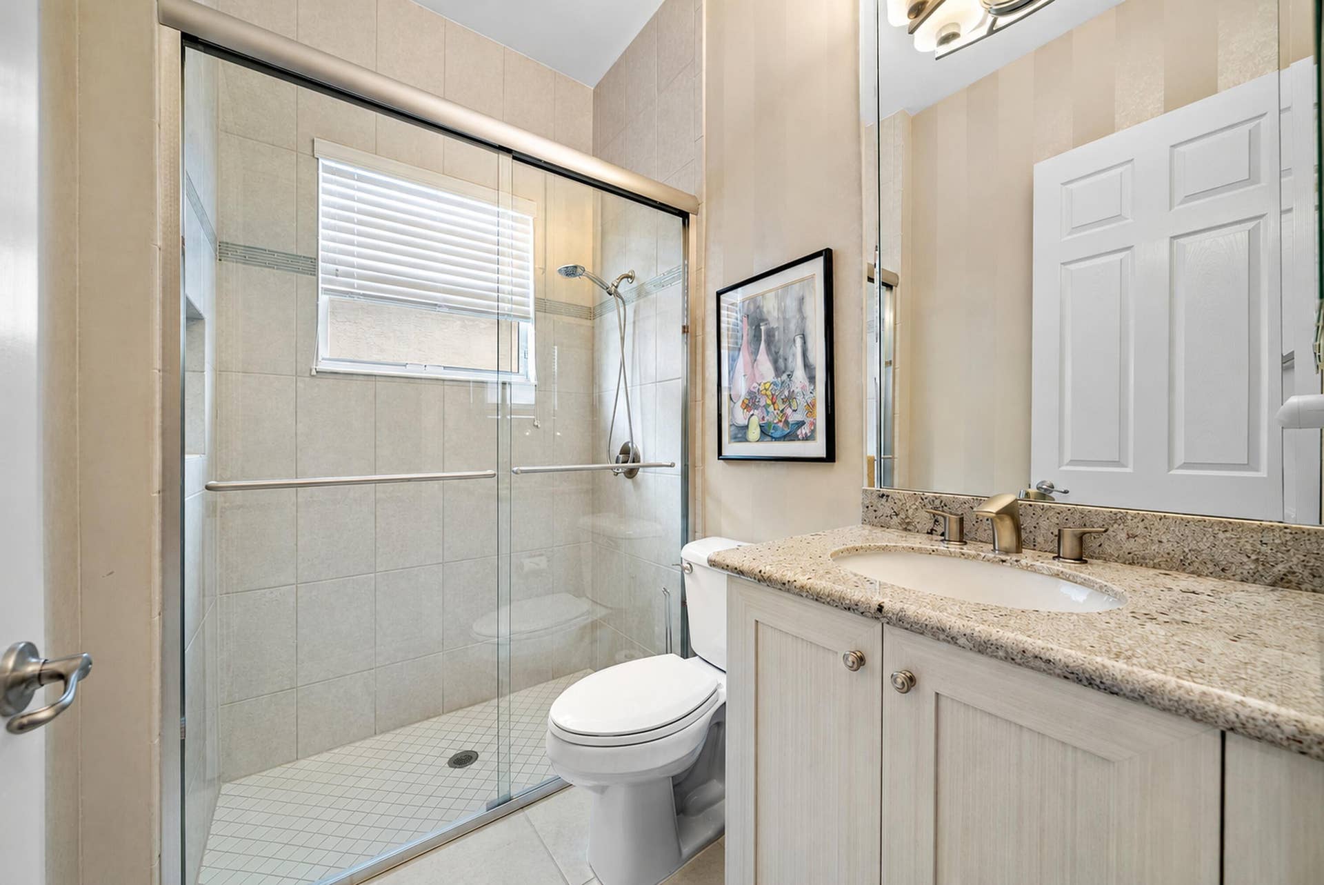 Bathroom featuring a shower with a sliding glass door, tiled wall surround, and a stone-surface vanity with an integrated basin