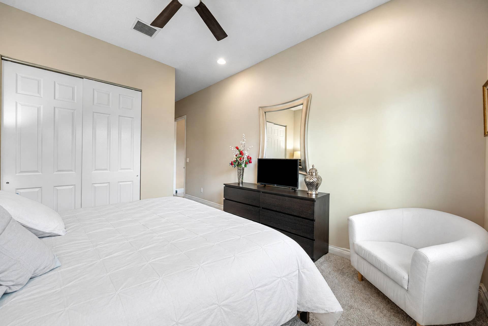 Neutral-toned interior featuring carpeting, a ceiling fan, and sliding closet doors