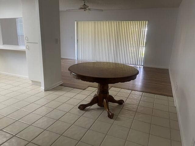 Interior space featuring large-format ceramic tile flooring, wood-finish flooring, a pass-through opening, and floor-to-ceiling vertical blinds