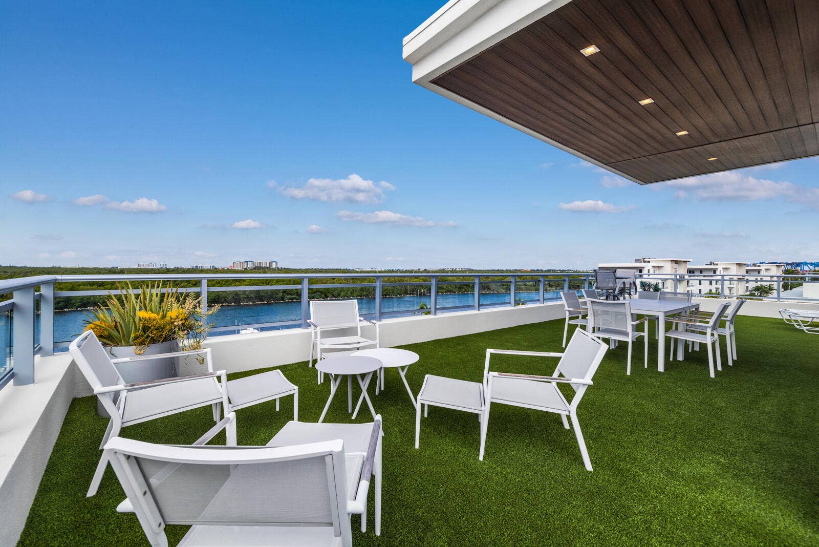 Expansive rooftop terrace featuring synthetic turf, a covered ceiling with recessed lighting, and a metal railing