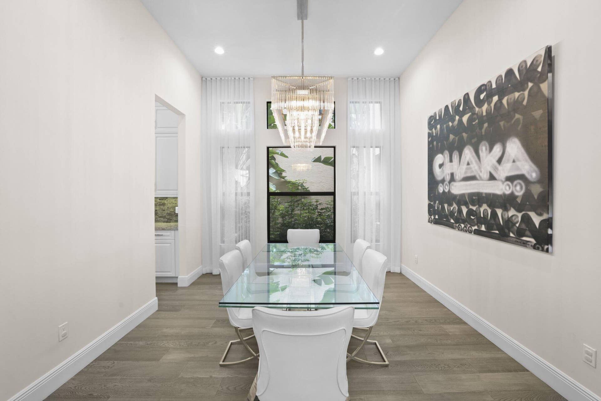 Wood-finish flooring with crisp white baseboards, complemented by a modern chandelier