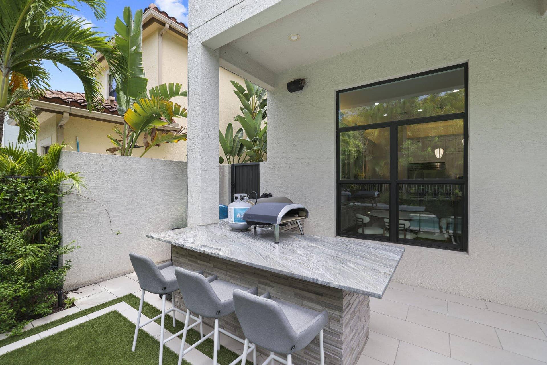 Covered outdoor bar with a stone-finish base, substantial counter, and paved patio