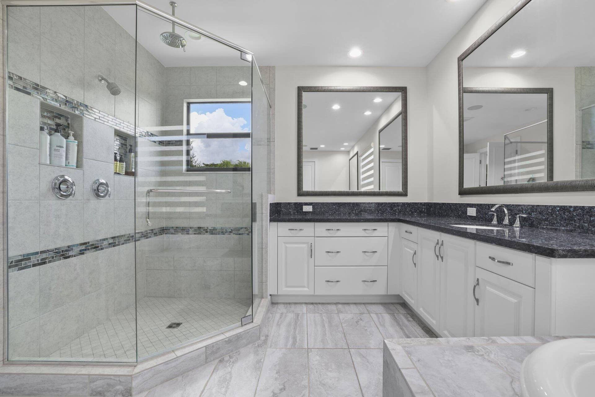 Frameless glass shower enclosure with dual shower heads and tiled niches