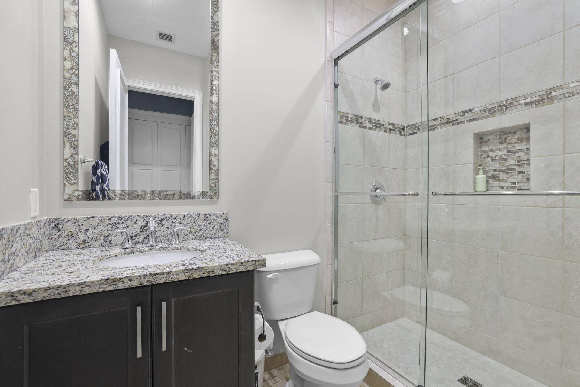 Vanity with stone countertop, undermount sink, and dark wood-finish cabinetry